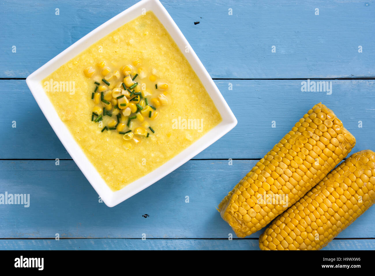 Soupe de maïs dans un bol blanc sur bleu fond de bois.copyspace Banque D'Images