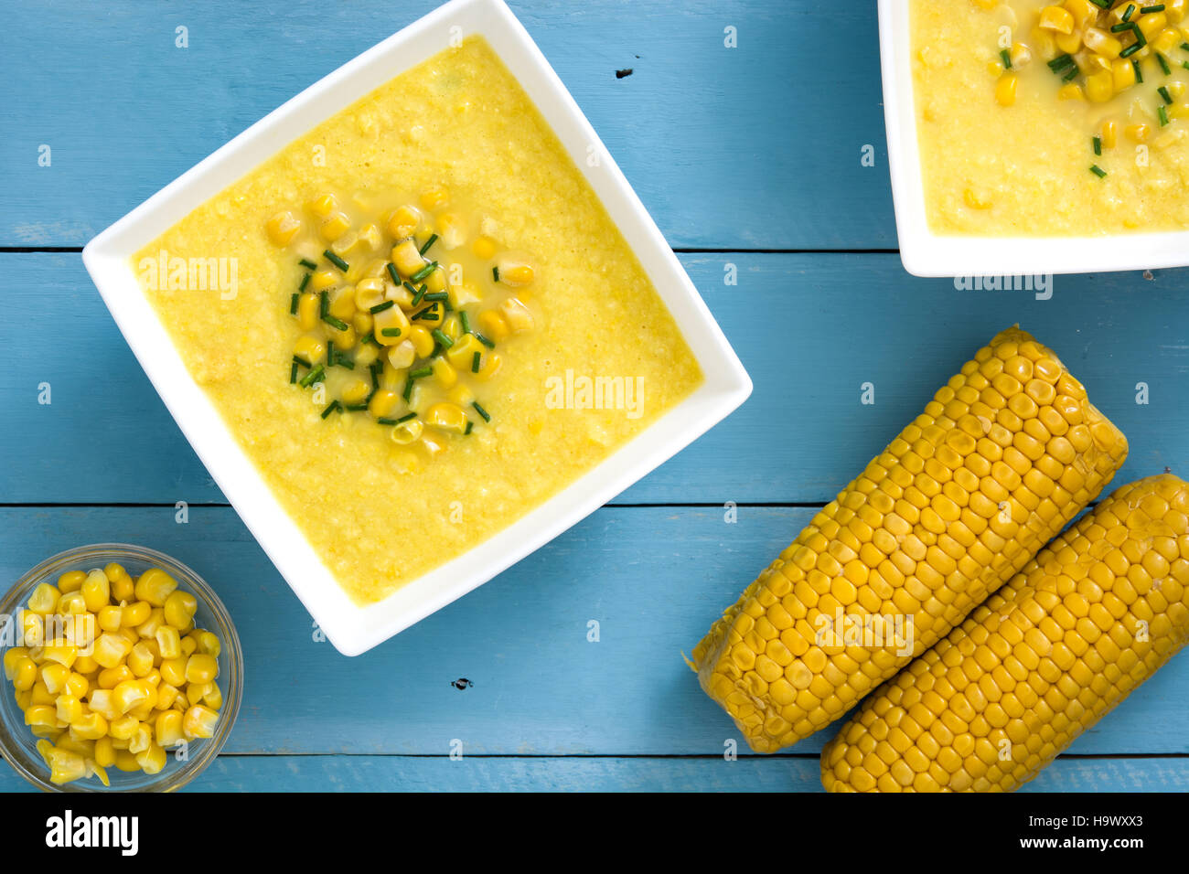 Soupe de maïs dans un bol blanc sur bleu fond de bois.copyspace Banque D'Images