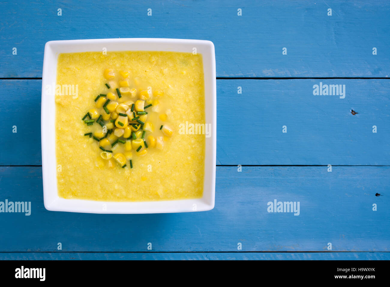 Soupe de maïs dans un bol blanc sur bleu fond de bois.copyspace Banque D'Images