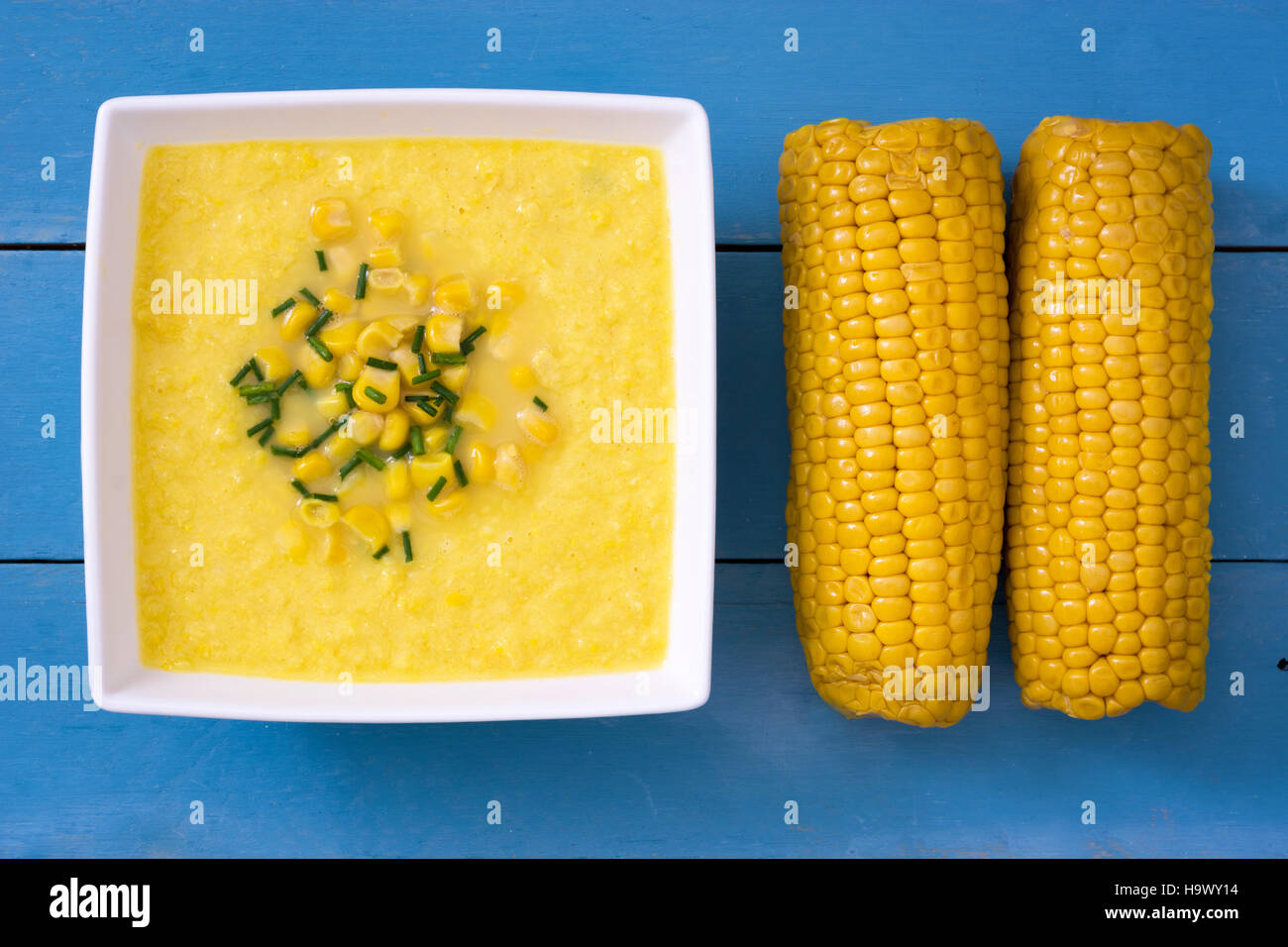 Soupe de maïs dans un bol blanc sur bleu fond de bois.copyspace Banque D'Images