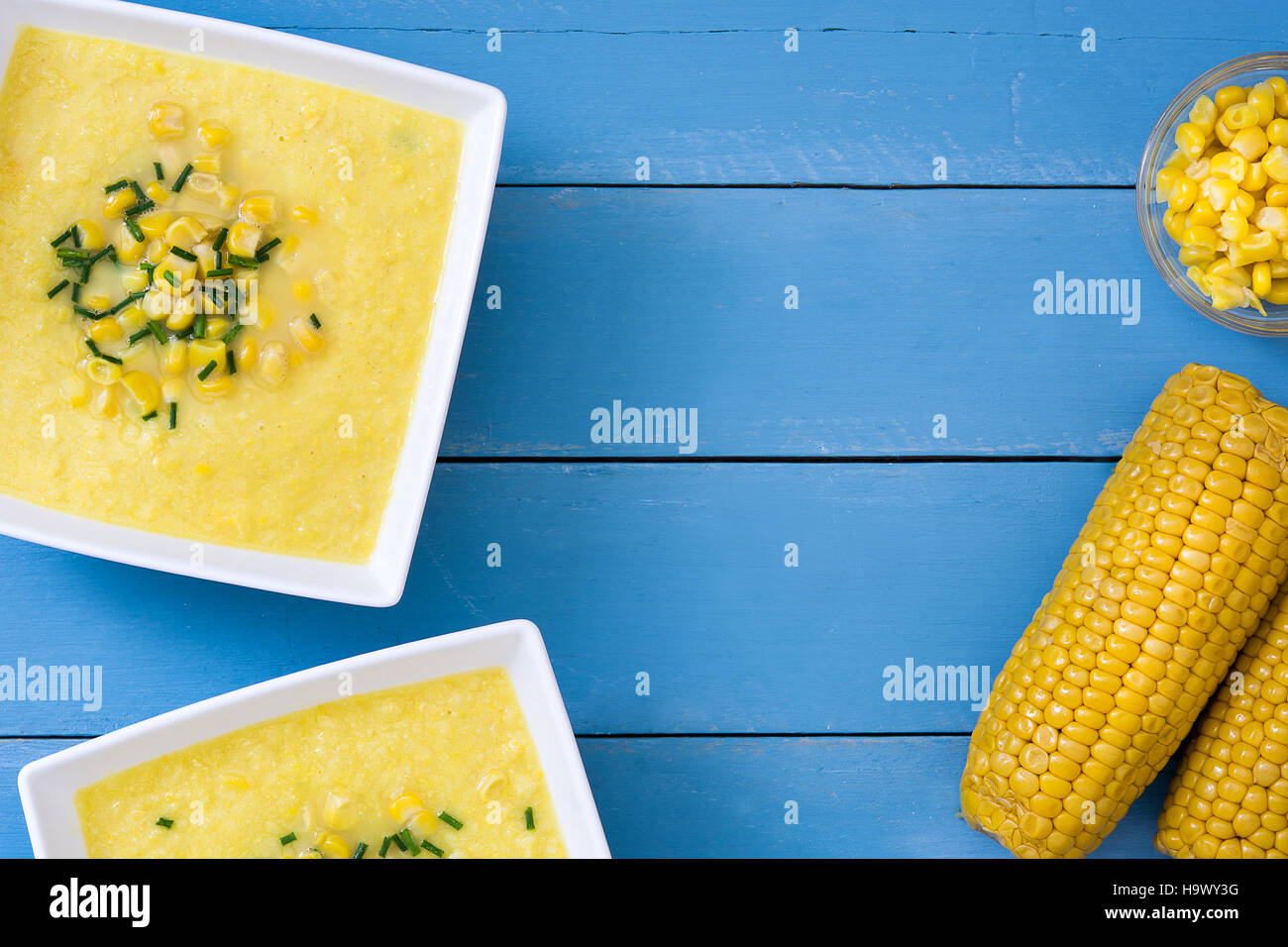 Soupe de maïs dans un bol blanc sur bleu fond de bois.copyspace Banque D'Images