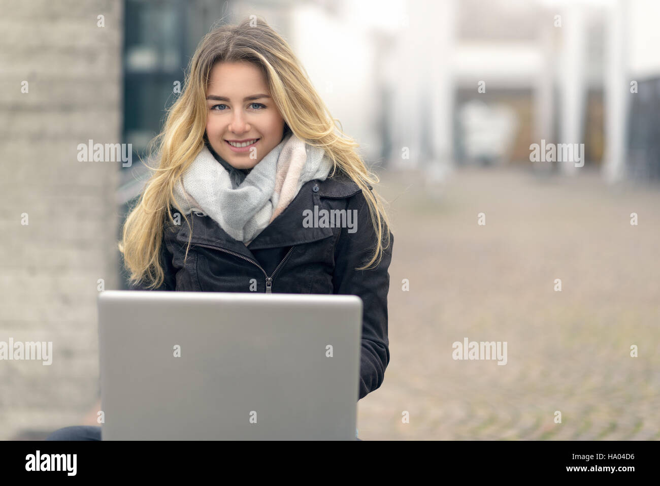 Jeune femme blonde travaille sur son ordinateur portable tout en étant assis sur un banc à l'extérieur, l'éducation et l'étude concept Banque D'Images