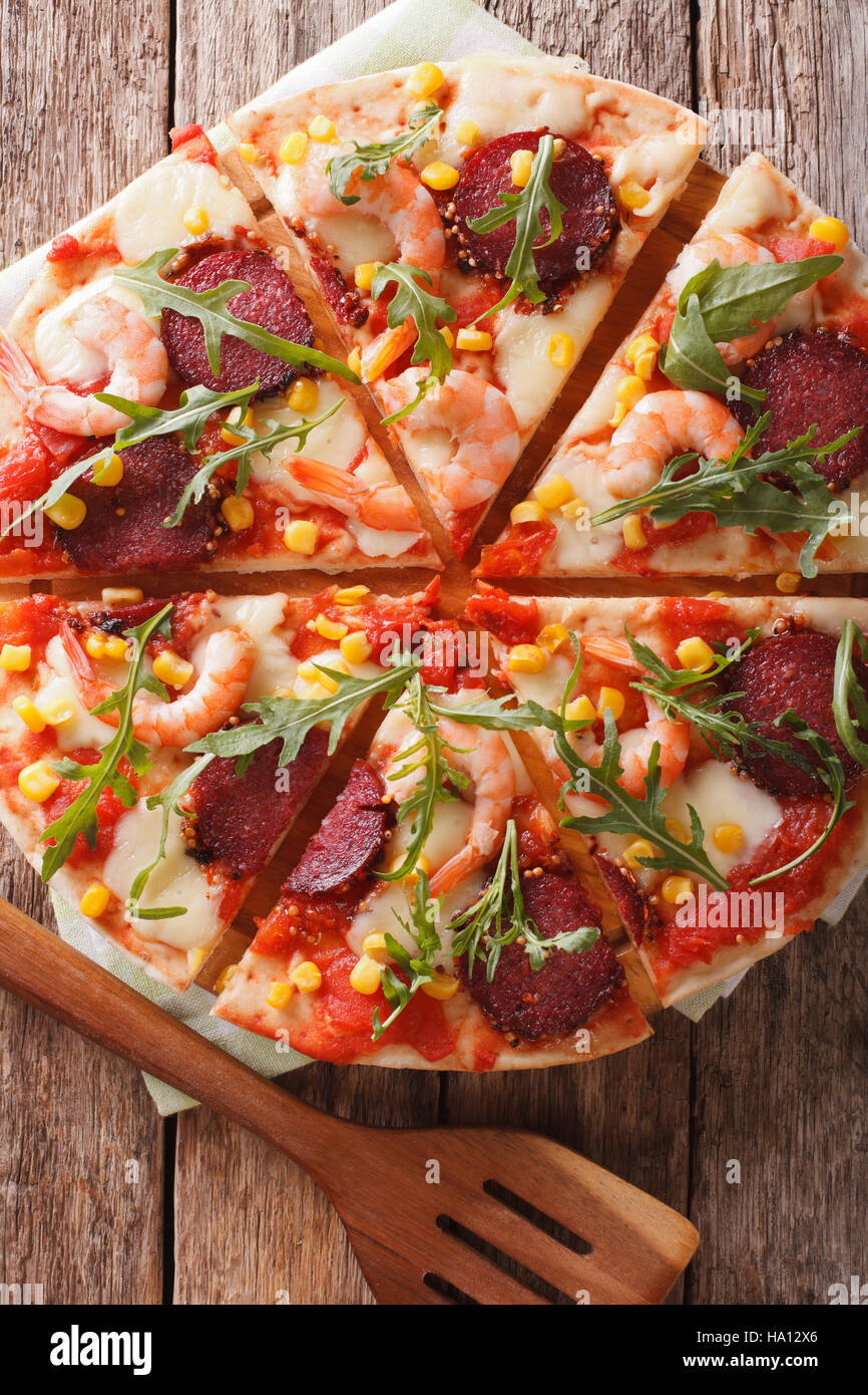 Tranches de pizza aux crevettes, salami, fromage et roquette close-up sur une planche en bois. vertical Vue de dessus Banque D'Images