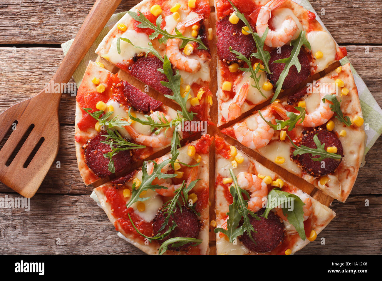 Tranches de pizza aux crevettes, salami, fromage et roquette close-up sur une planche de bois. Vue du dessus horizontale Banque D'Images