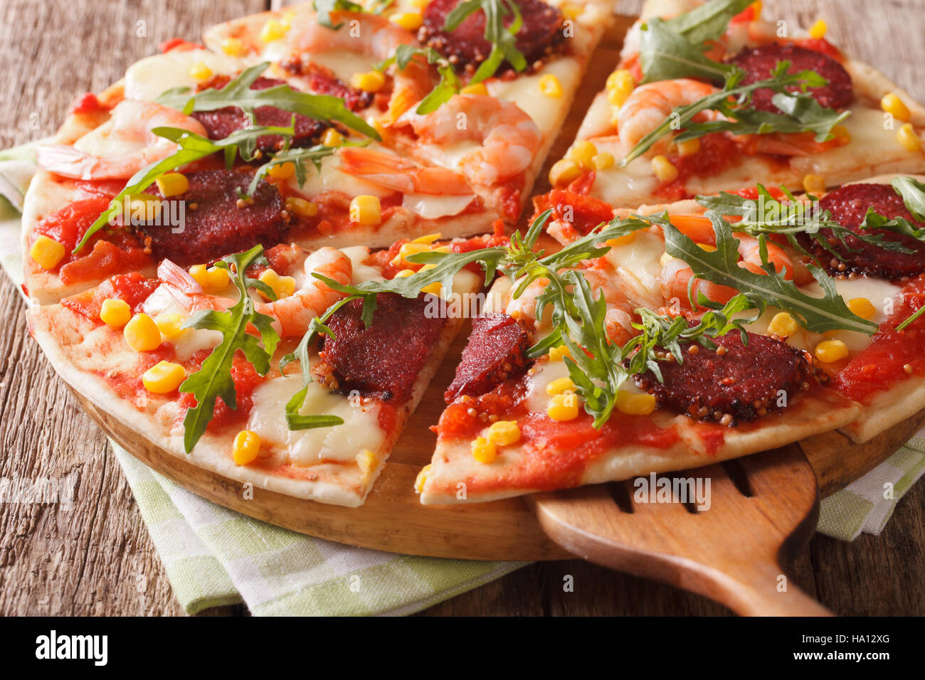 Tranches de pizza aux crevettes, salami, fromage et roquette close-up sur une planche de bois horizontal. Banque D'Images