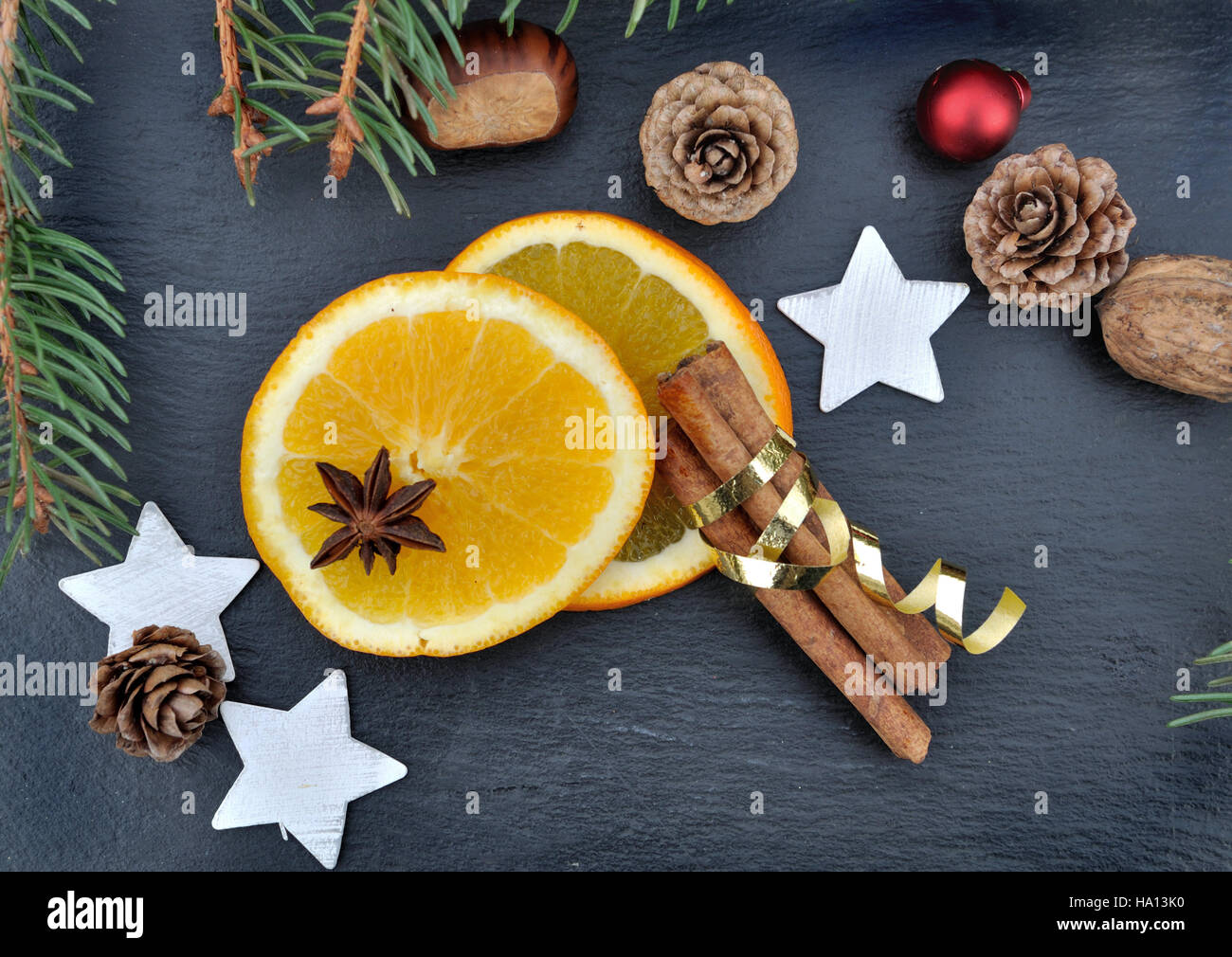 La cannelle, l'anis et les tranches d'orange parmi les décorations de Noël sur fond d'ardoise Banque D'Images