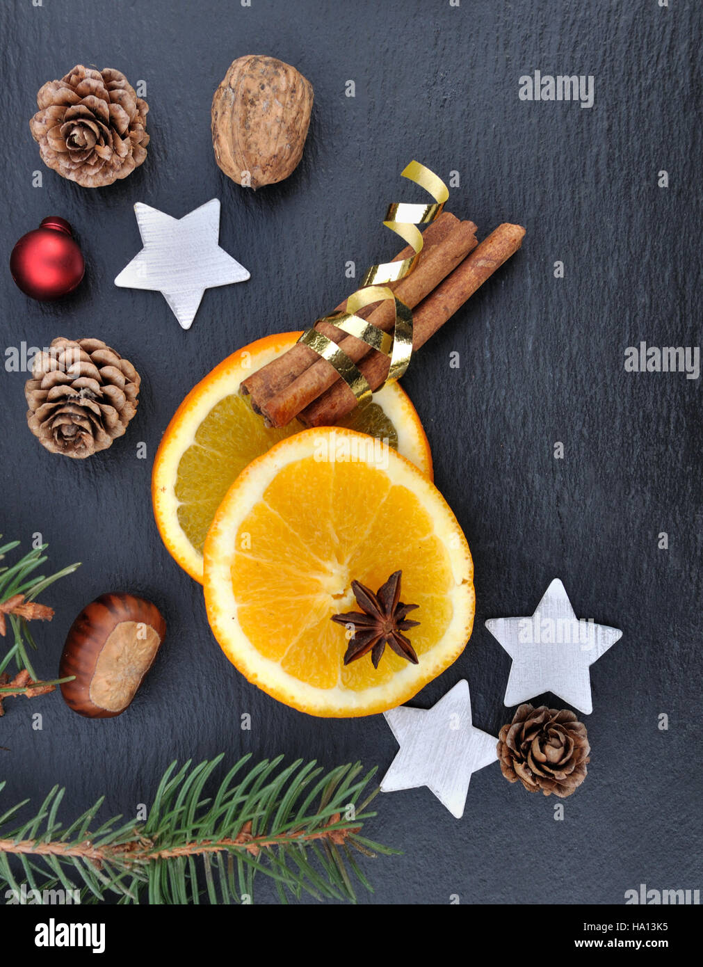 La cannelle, l'anis et les tranches d'orange parmi les décorations de Noël sur fond d'ardoise Banque D'Images