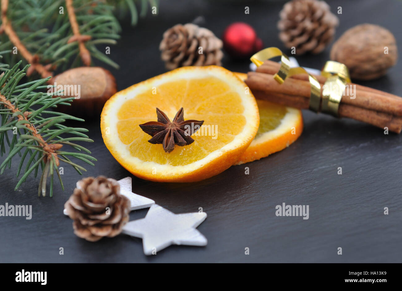 La cannelle, l'anis et les tranches d'orange parmi les décorations de Noël sur fond d'ardoise Banque D'Images