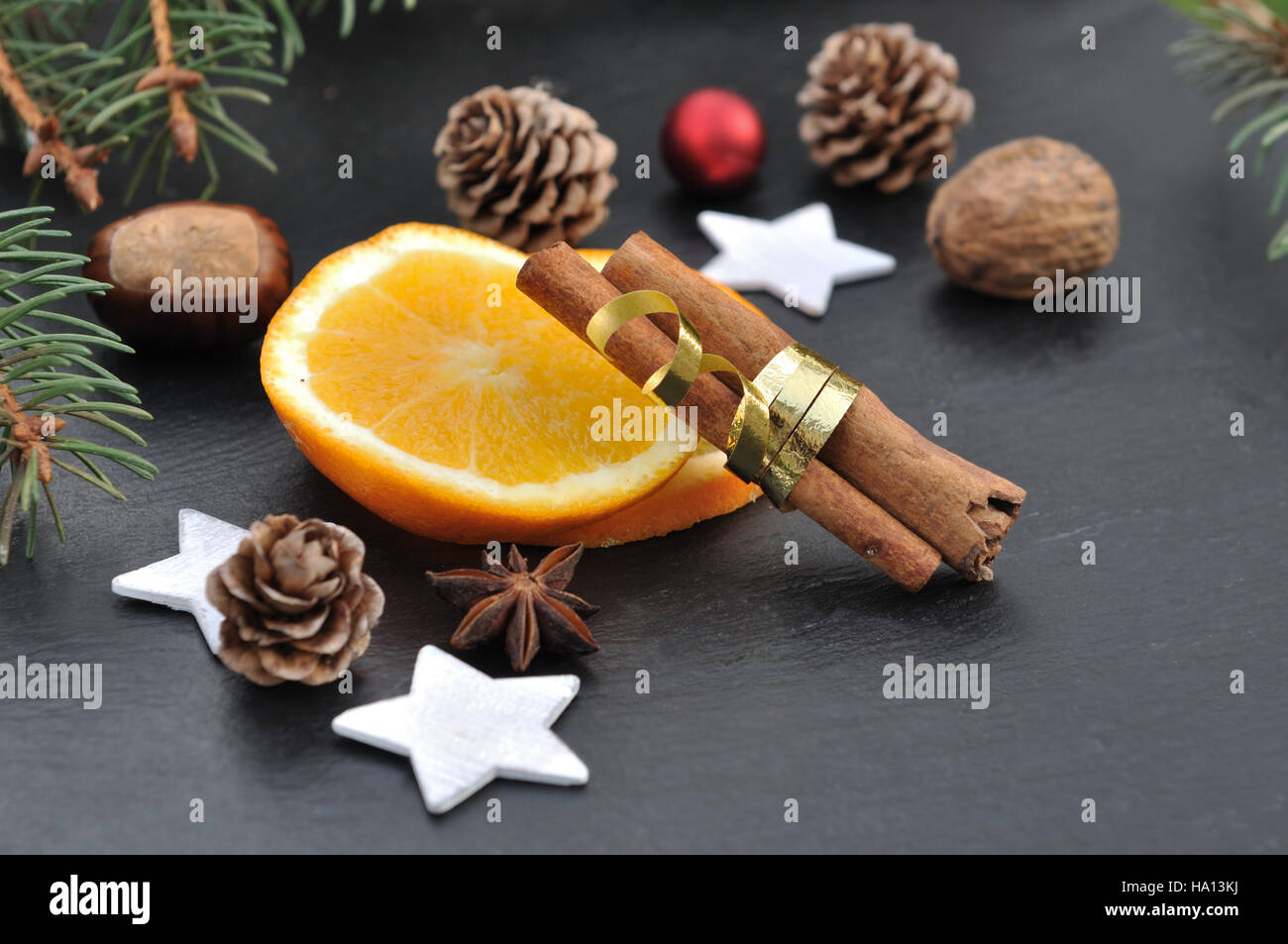La cannelle, l'anis et les tranches d'orange parmi les décorations de Noël sur fond d'ardoise Banque D'Images