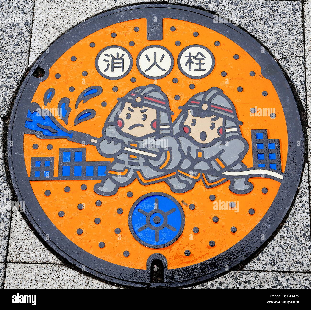 Fer ronde couvercle pour les pompiers de ponceaux.s utilisez décoré avec un dessin de pompiers luttent contre le feu sur le sol d'une rue du centre-ville. Roppongi Banque D'Images