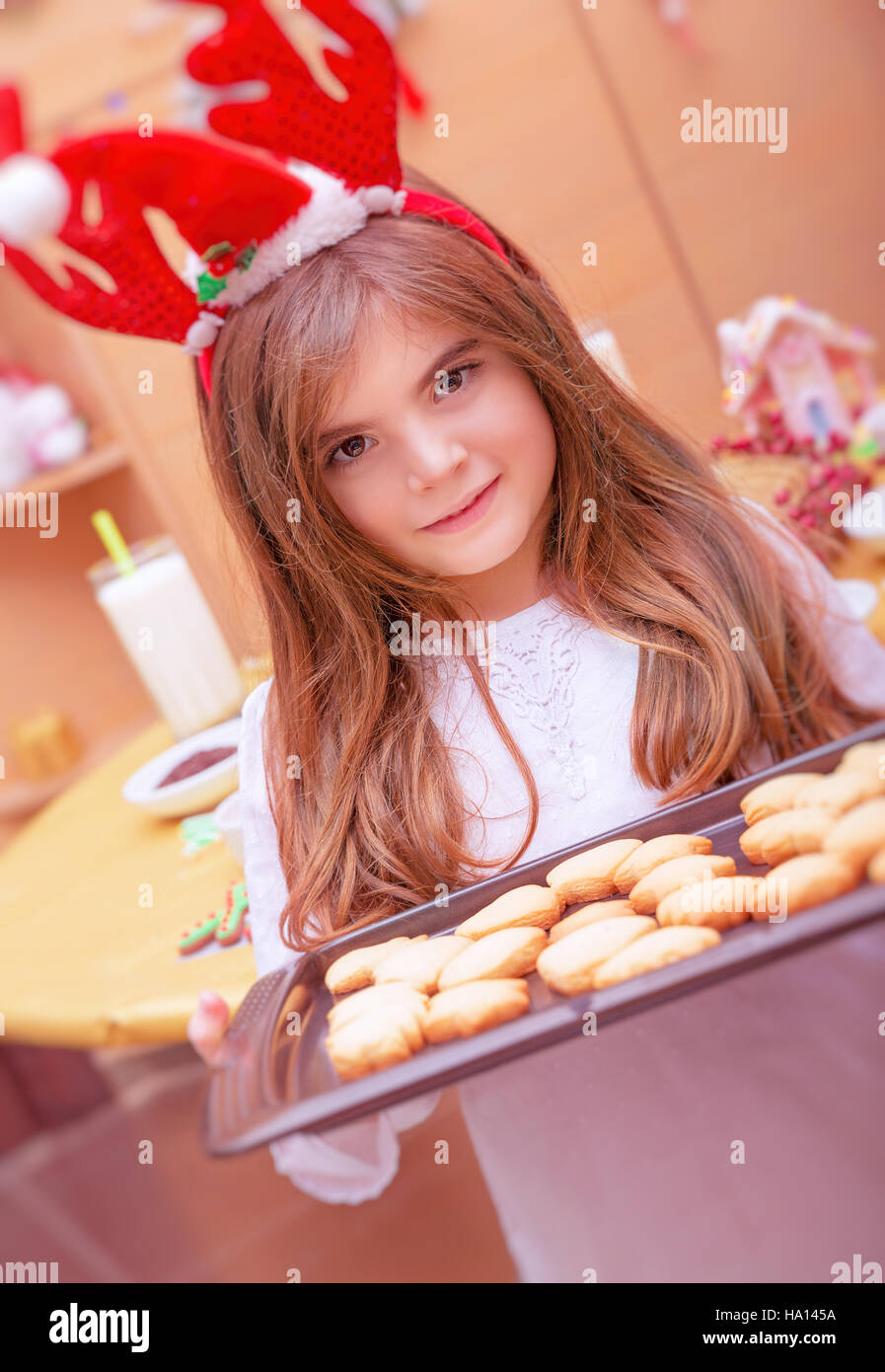 Cute petite fille debout dans la cuisine Avec lèchefrite pleine de cookies de fête, petit Père helper, préparation traditionnelle pour les vacances de Noël Banque D'Images