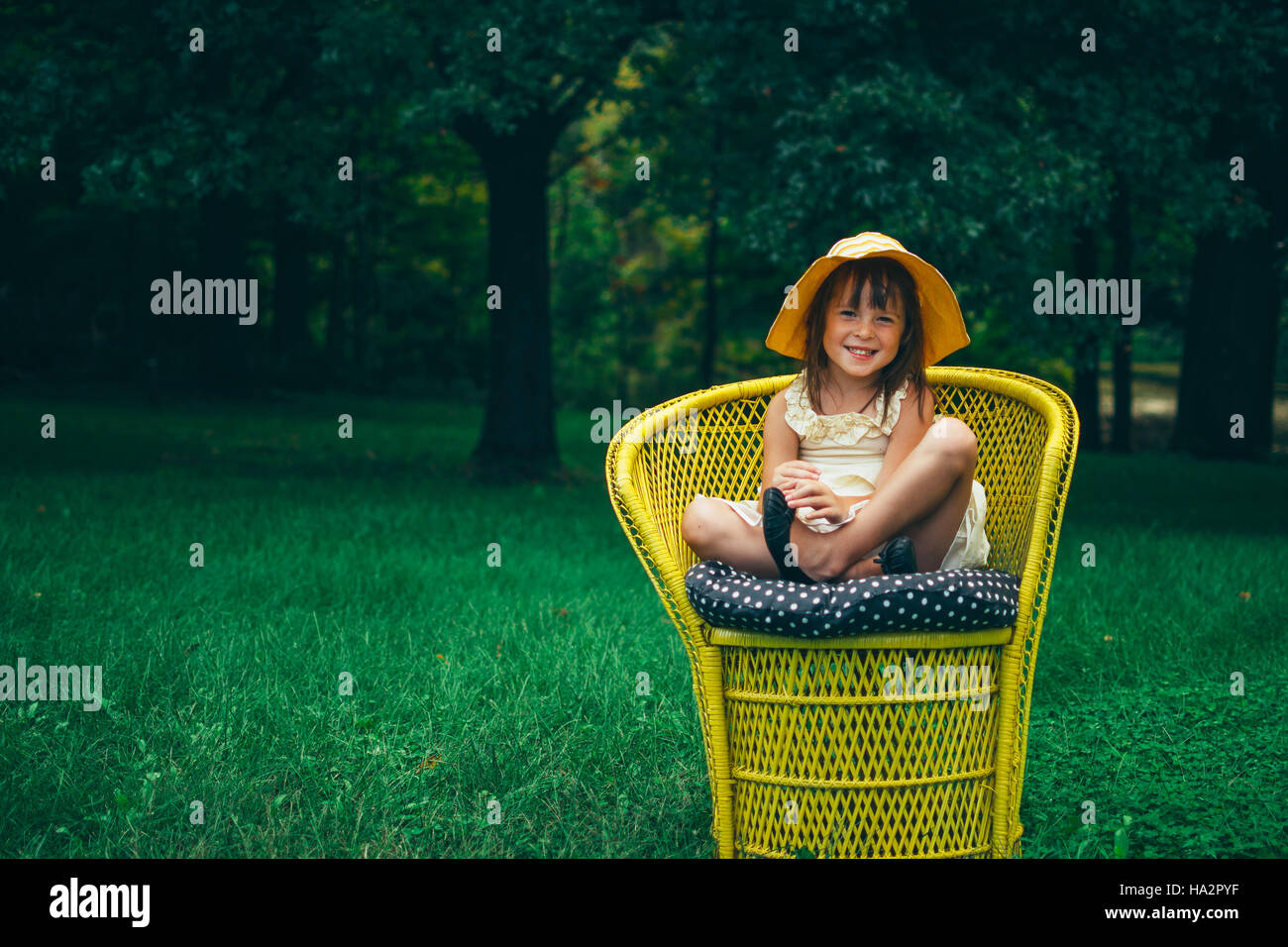 Portrait of a smiling girl sitting dans un fauteuil de jardin Banque D'Images