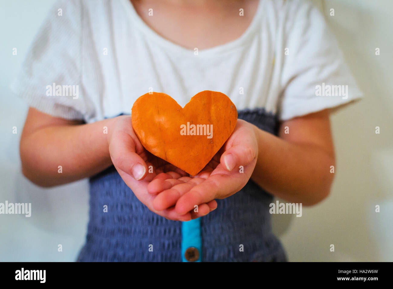 Girl holding heart shaped pumpkin Banque D'Images