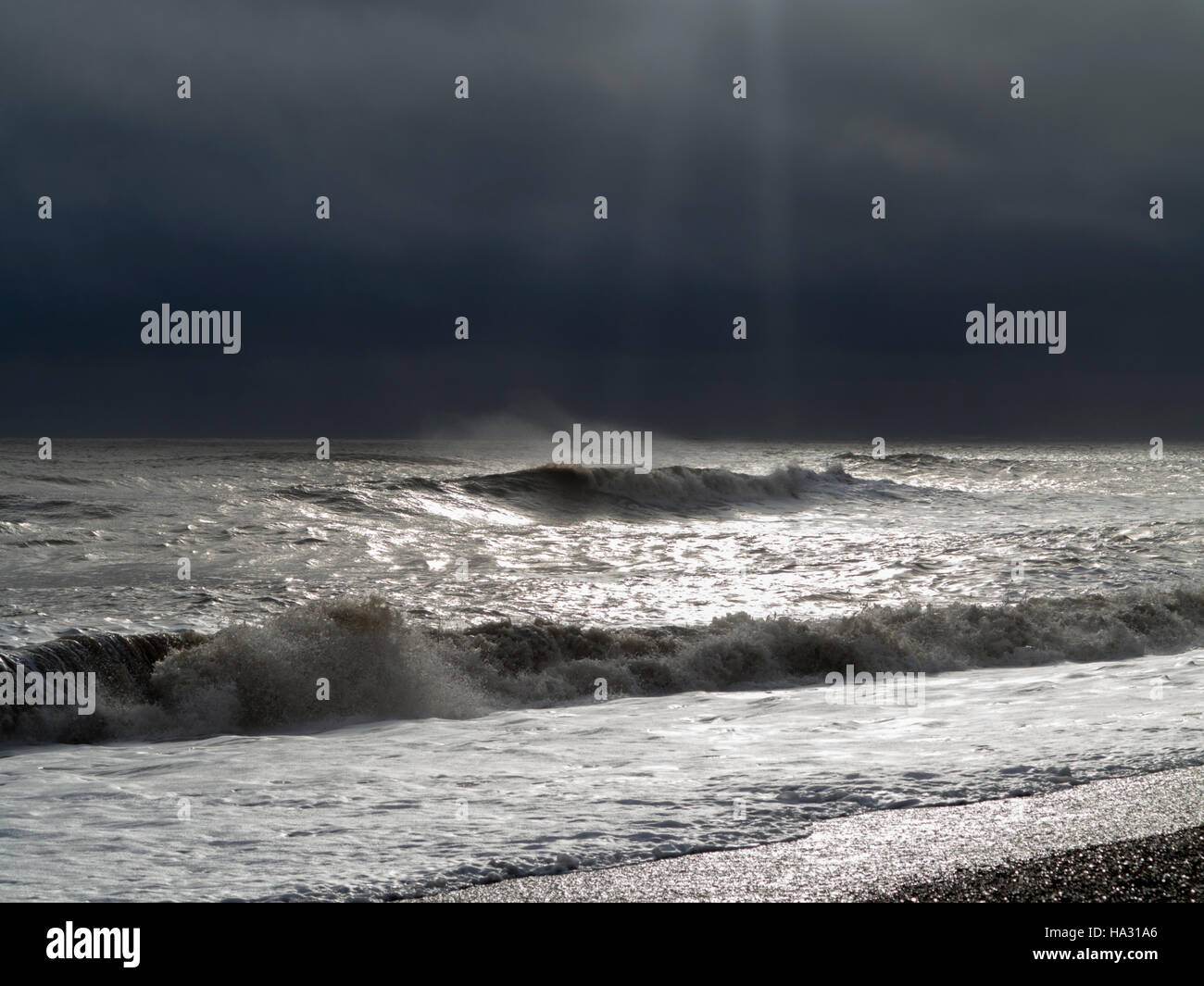 Multiplication des vagues se brisant sur la rive pendant les grands vents et de pulvérisation avec de la mousse à l'avant-plan et d'un ciel menaçant Banque D'Images