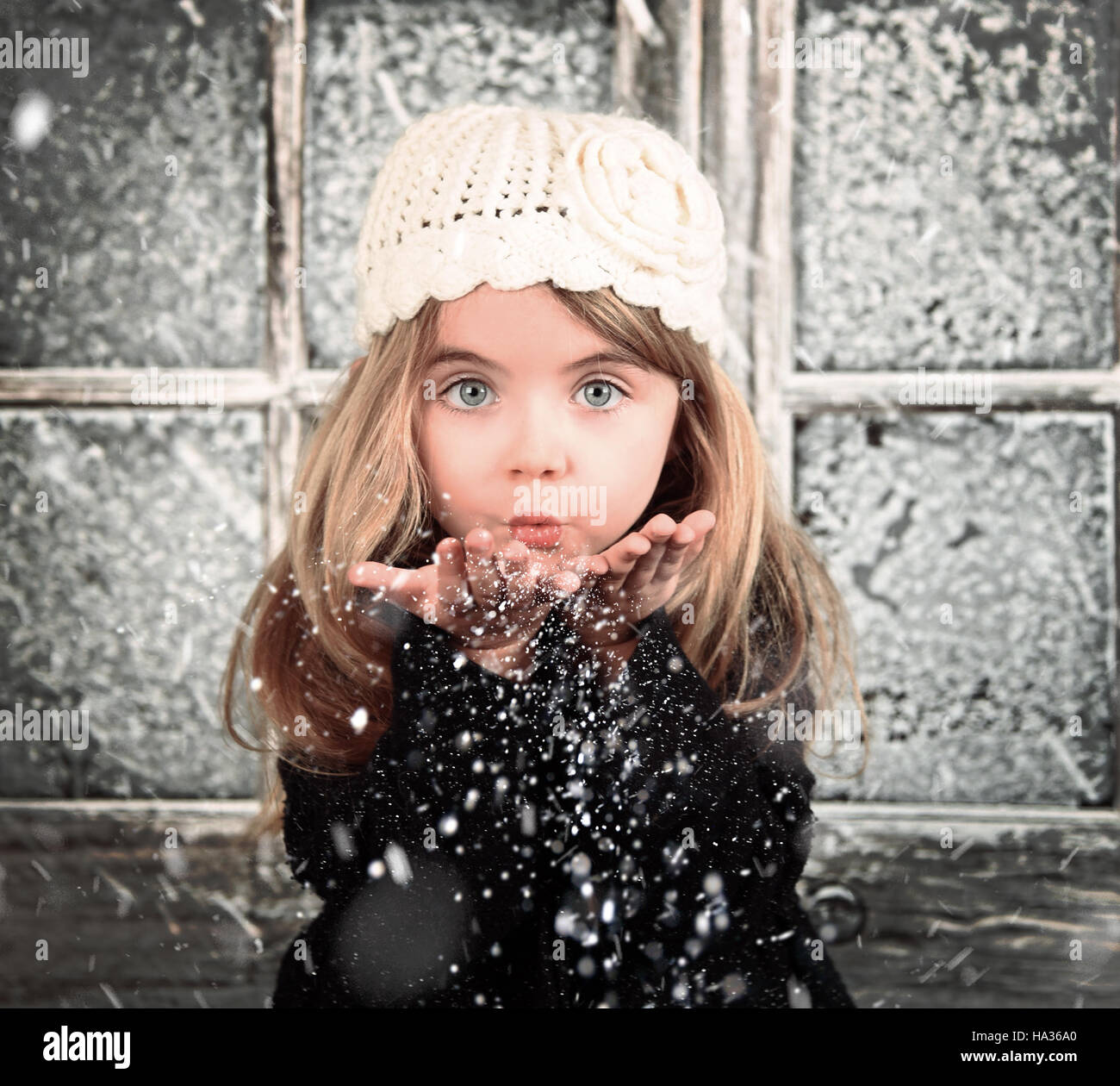 Un jeune enfant est blanc dans un souffle les flocons de l'hiver pour une scène d'arrière-plan ou de la saison de Noël de concept. Banque D'Images