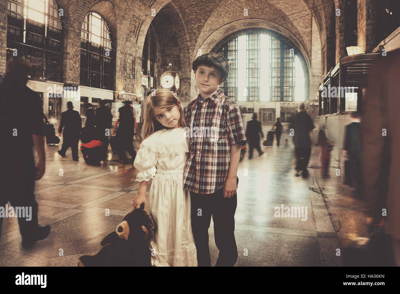 Deux jeunes enfants voyageur vintage sont debout dans une ancienne gare en attente de transport pour un voyage imaginaire ou le concept. Banque D'Images