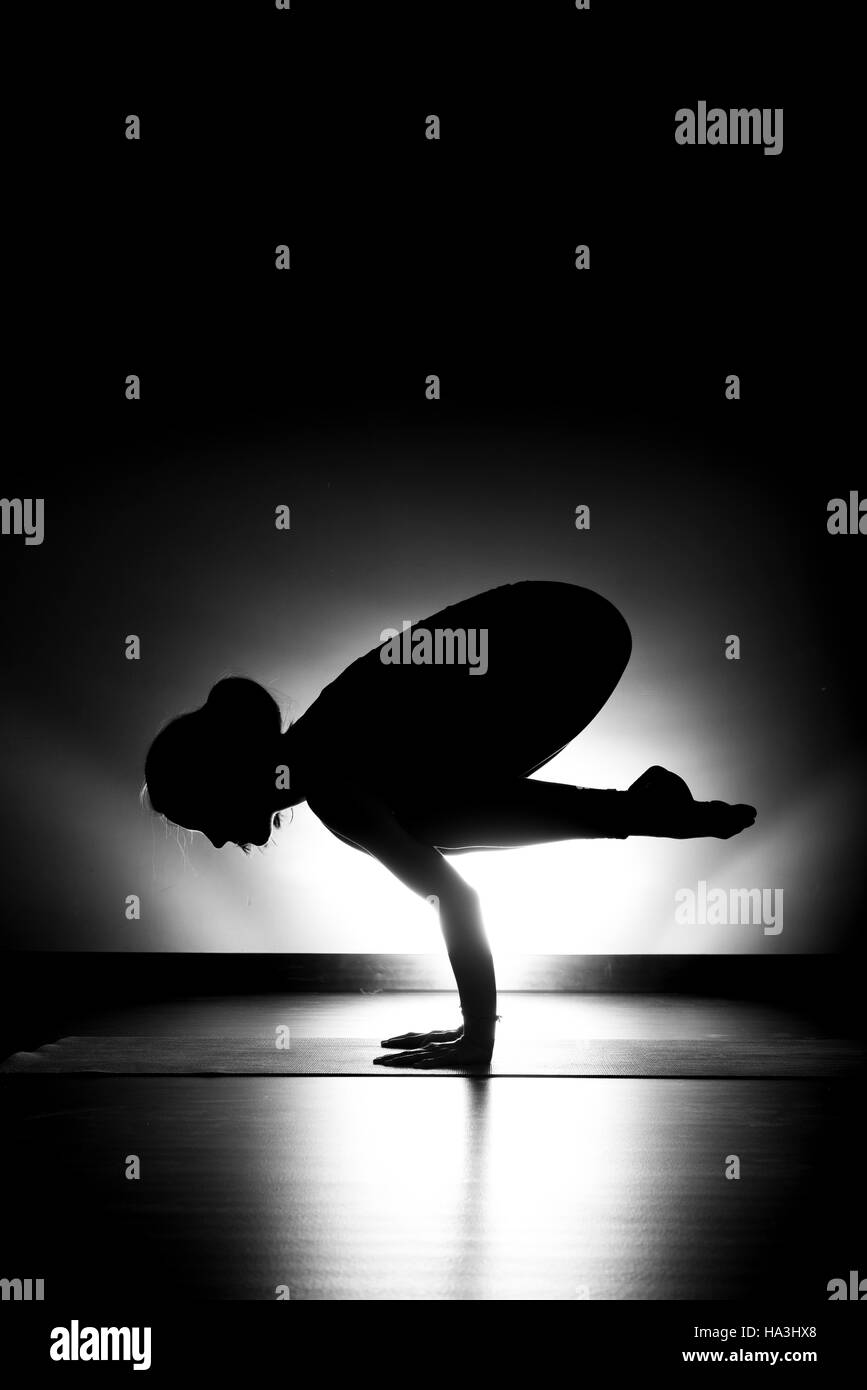 Woman doing yoga posture du corbeau noir et blanc silhouette en studio Banque D'Images