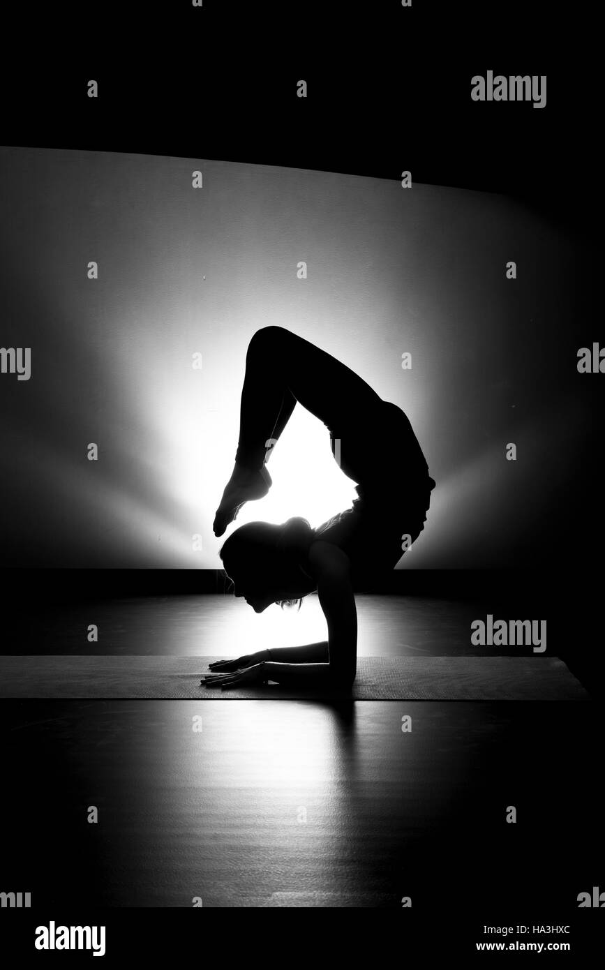 Woman doing yoga pose scorpion silhouette noir et blanc en studio Banque D'Images