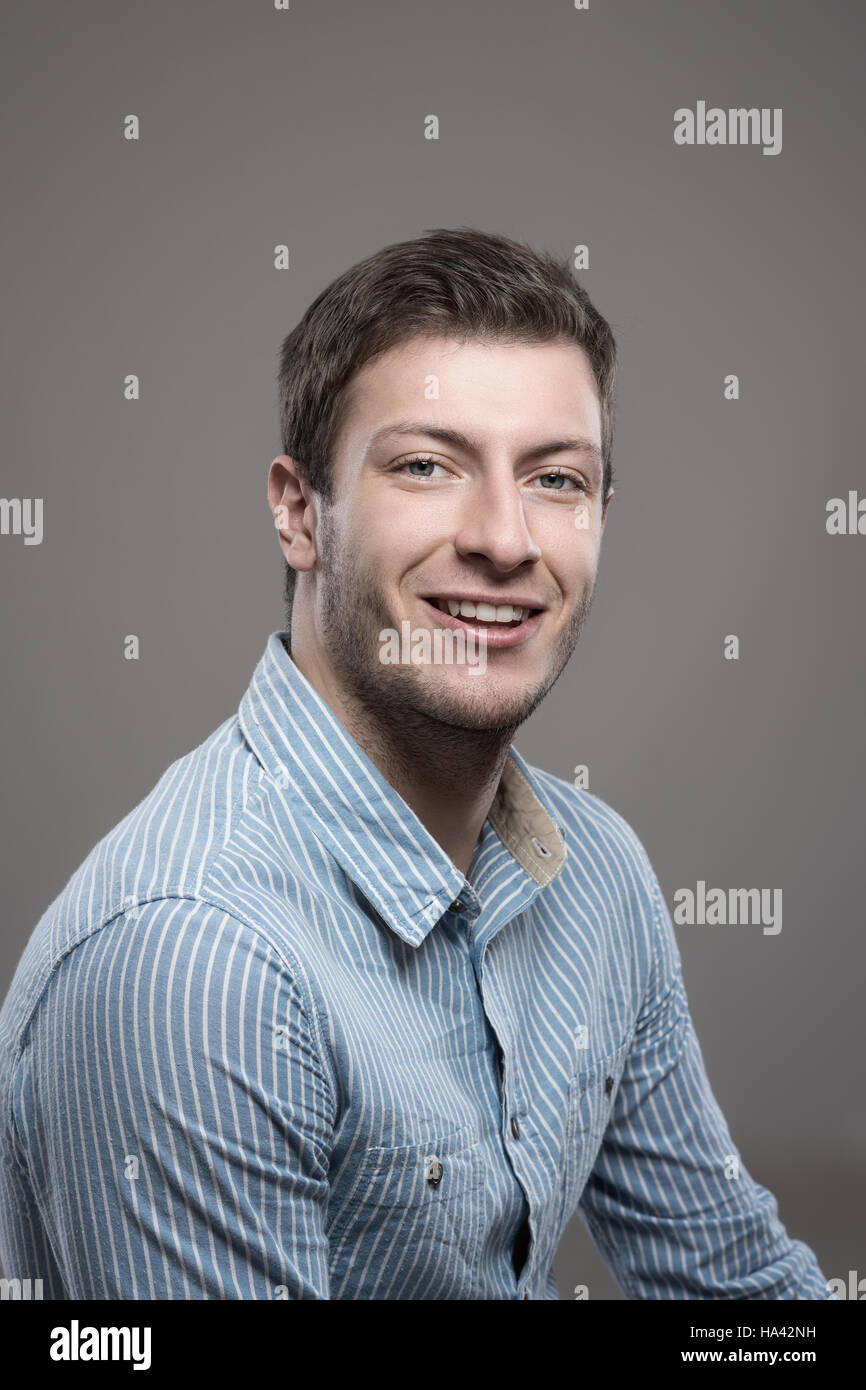 Portrait de jeunes Moody pdg businessman smiling at camera sur fond gris studio Banque D'Images
