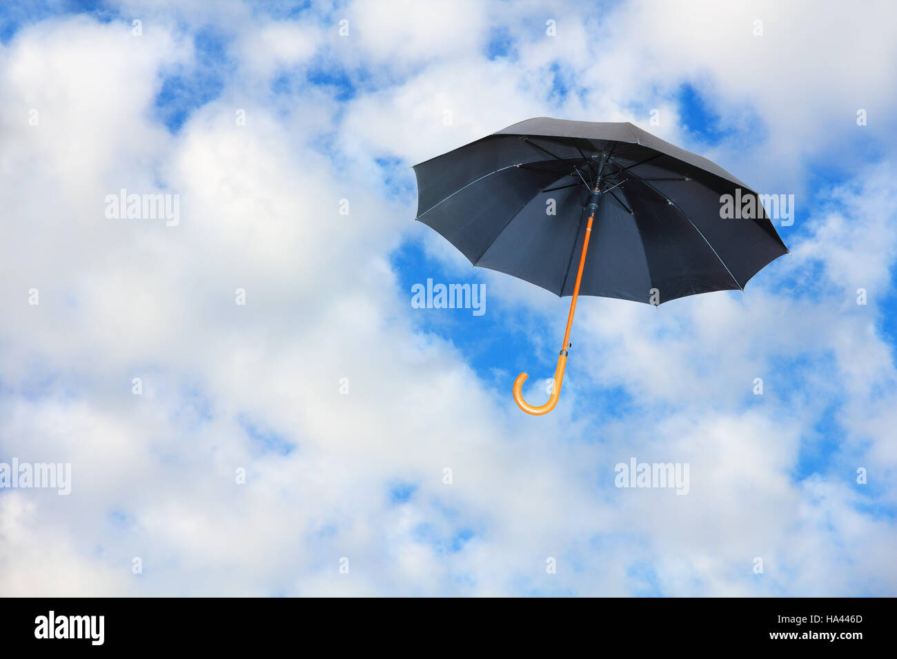 Parapluie noir vole dans le ciel contre des nuages d'un blanc pur.Mary Poppins Umbrella.vent de changement concept. Banque D'Images