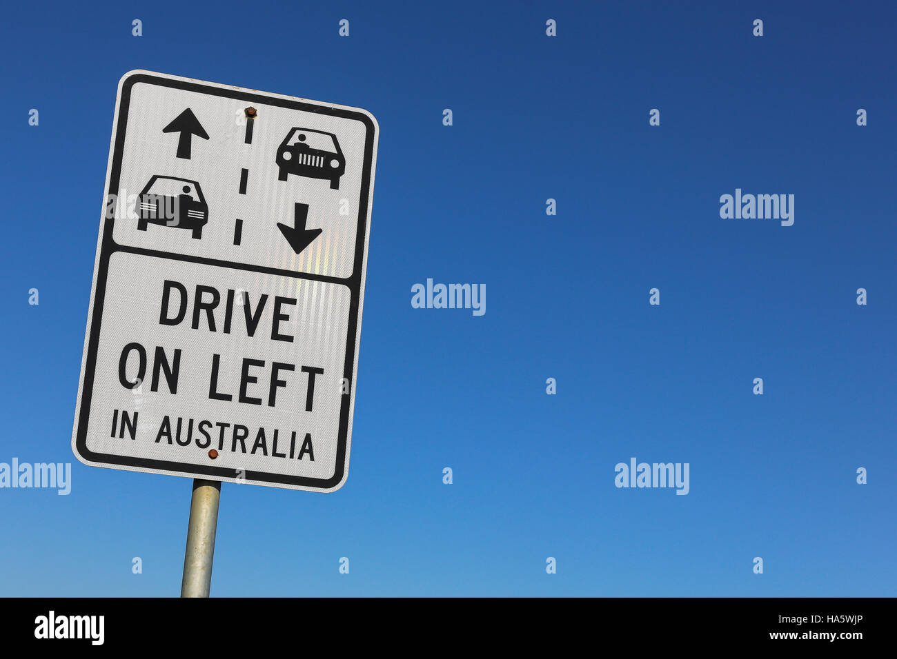 Conduire à gauche en Australie signe voiture contre un ciel bleu clair avec l'exemplaire de l'espace sur la droite Banque D'Images