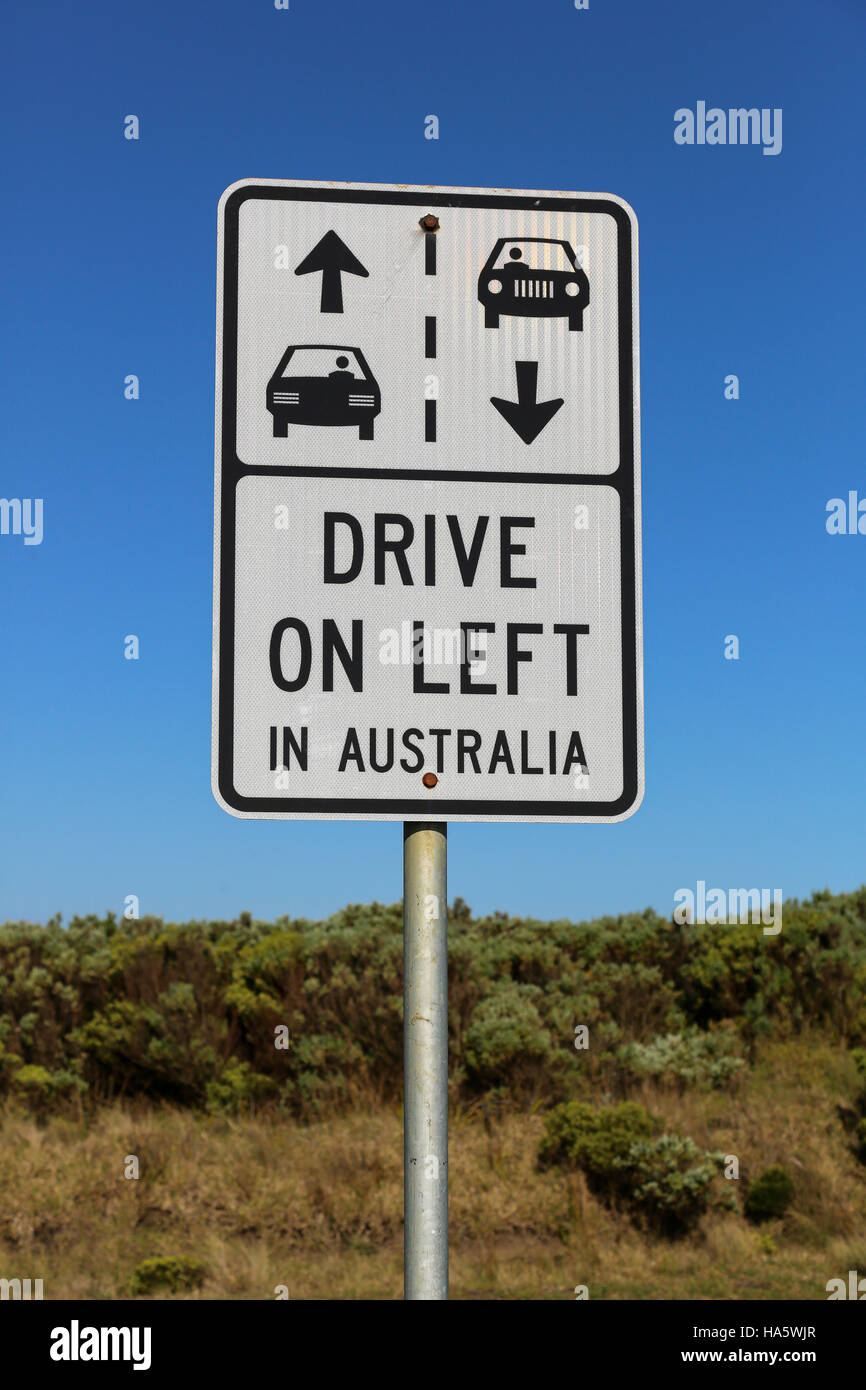 Conduire à gauche en Australie signer contre un ciel bleu clair et buissons verts sur la Great Ocean Road, près de Melbourne Banque D'Images