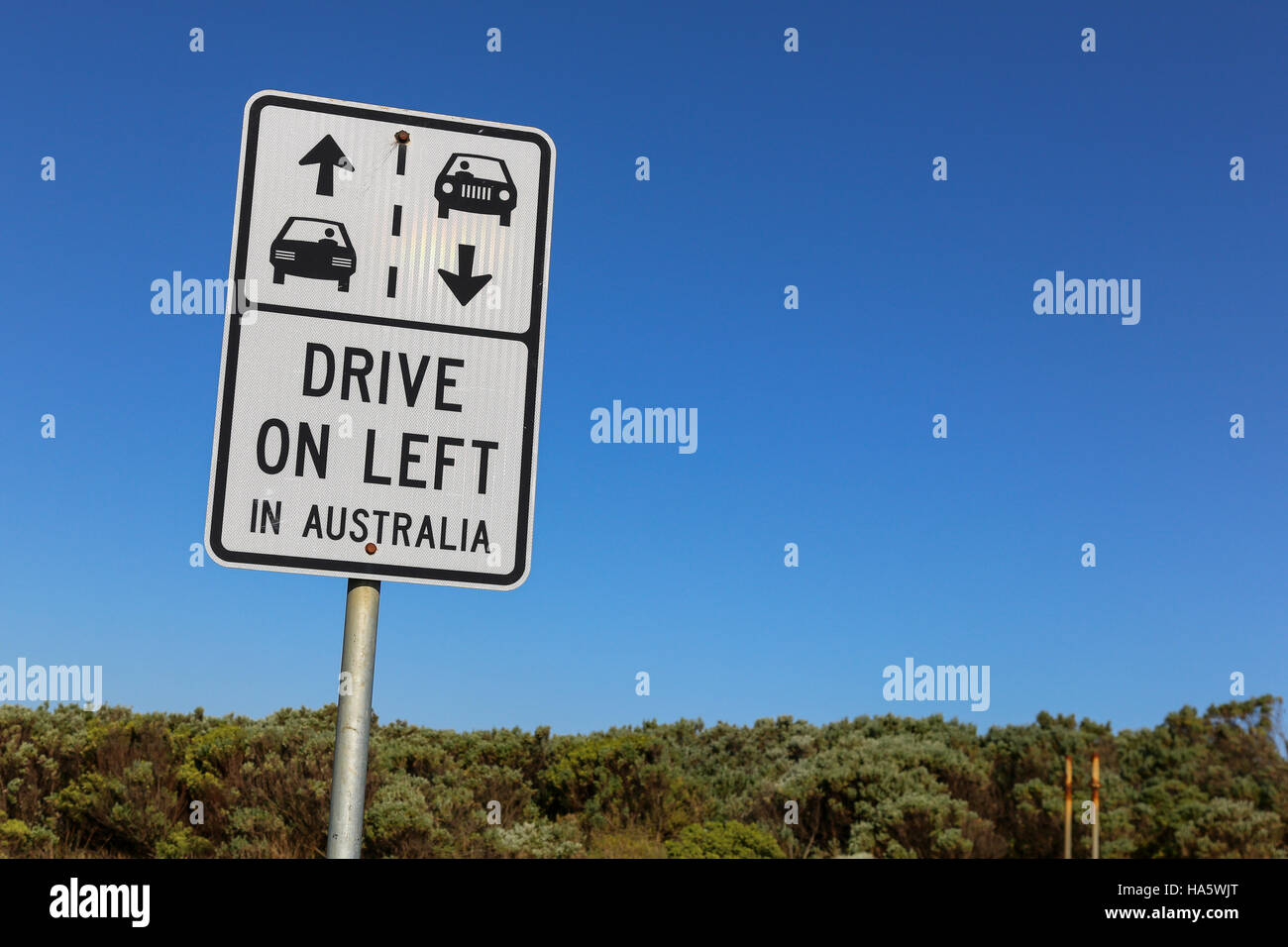 Conduire à gauche en Australie signe voiture contre un ciel bleu clair et buissons verts sur la Great Ocean Road, près de Melbourne Banque D'Images