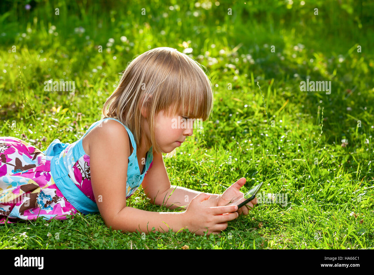 Petite fille à l'aide d'une tablette tactile dans un jardin d'été Banque D'Images