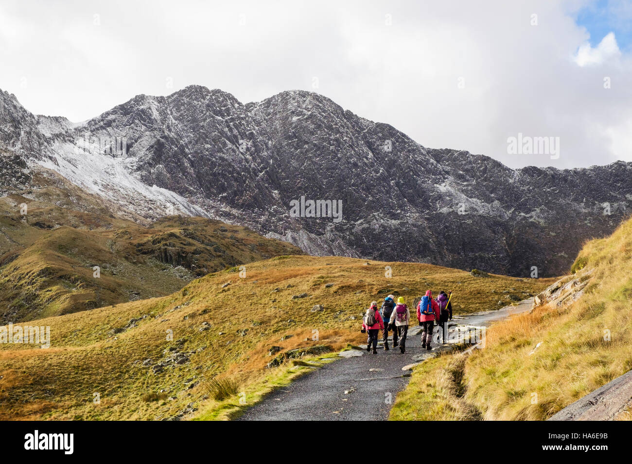 Les randonneurs randonnée sur la piste des mineurs dans Snowdon horseshoe avec Lliwedd Y de l'avant et la neige en hiver. Pen-y-Pass, Llanberis, Gwynedd, au nord du Pays de Galles, Royaume-Uni Banque D'Images