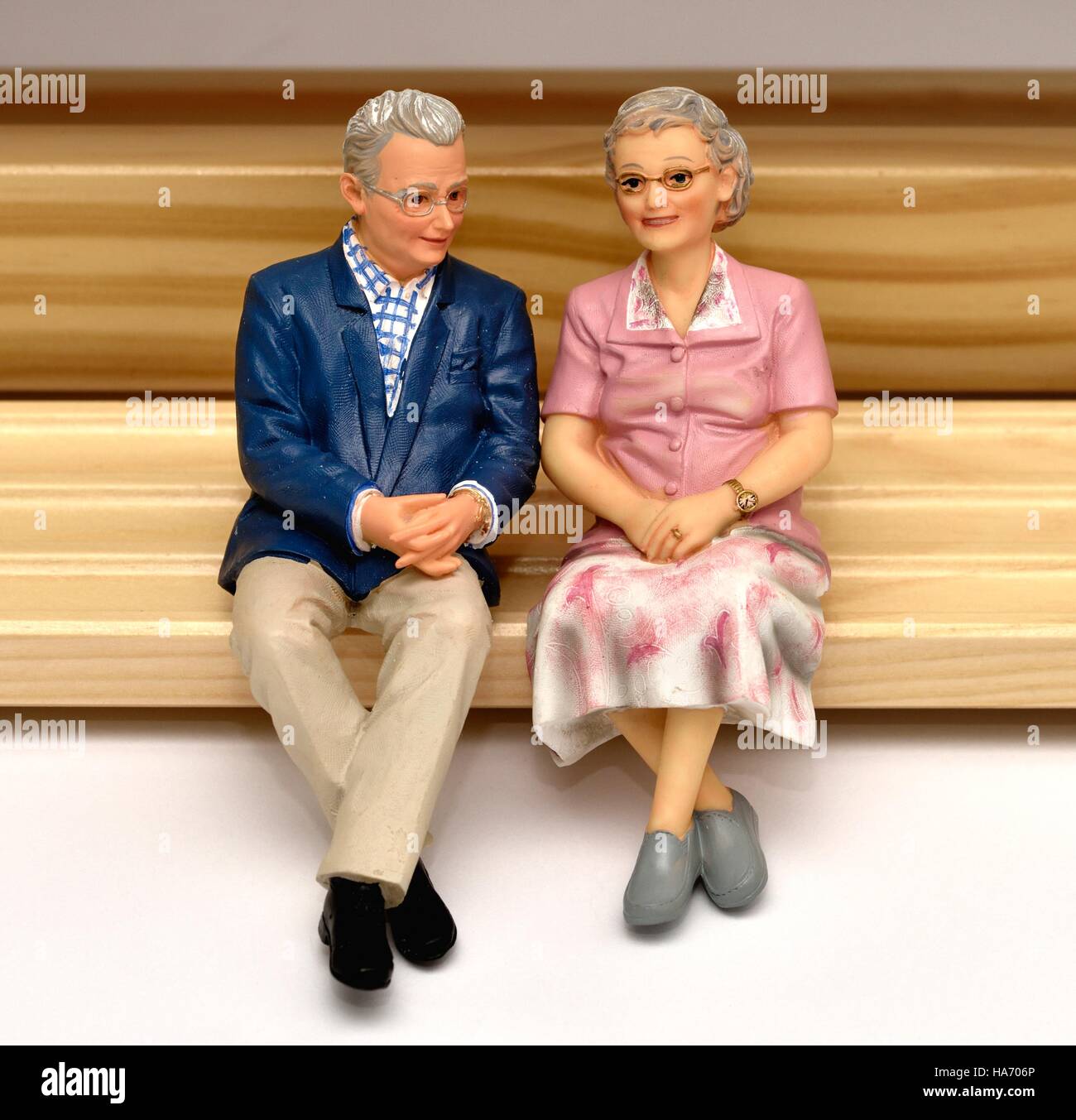 Personnes âgées une figurine miniature senior couple assis sur un banc en bois Banque D'Images