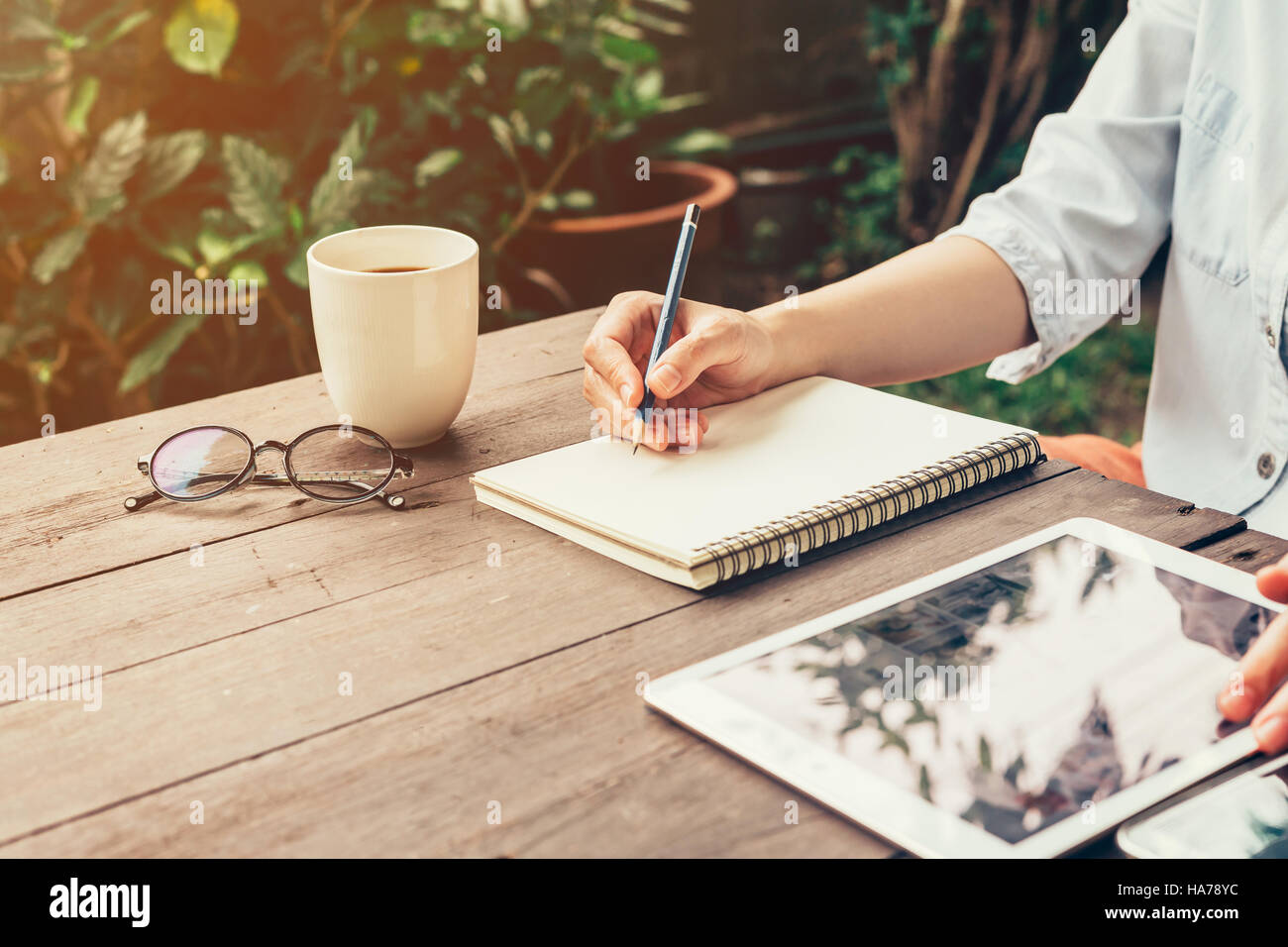 Jeune femme d'affaires la main avec crayon écrivant sur ordinateur portable. Femme part avec crayon écrivant sur un ordinateur portable et travailler au café. Banque D'Images