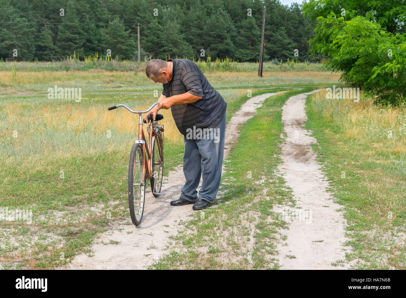 Les paysans ukrainiens debout sur une route de campagne et l'inspection de old rusty vélo pour se préparer à participer au Grand Tour cette saison Banque D'Images