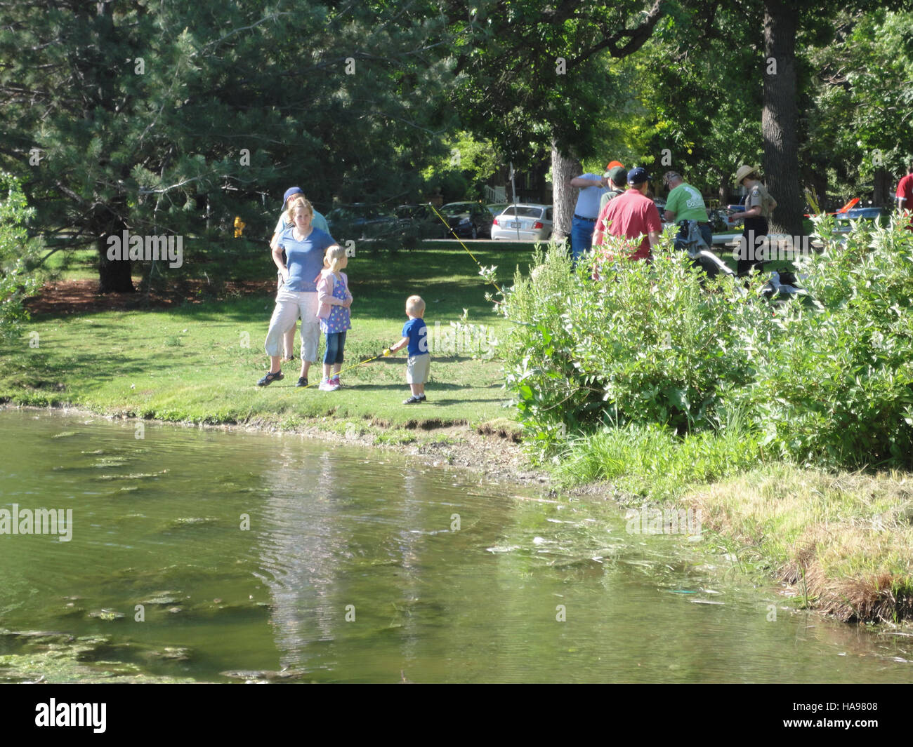 Cette photographie montre une famille pêchant la truite à City Park, qui fait partie de la région des Prairies des montagnes du U.S. Fish and Wildlife Service. Il met l’accent sur les activités récréatives de plein air et l’engagement de la communauté envers la nature. Banque D'Images