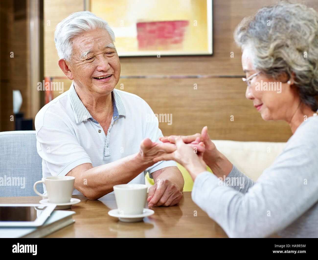 Senior femme essayant de lire la chiromancie de son mari alors que le café ensemble. Banque D'Images