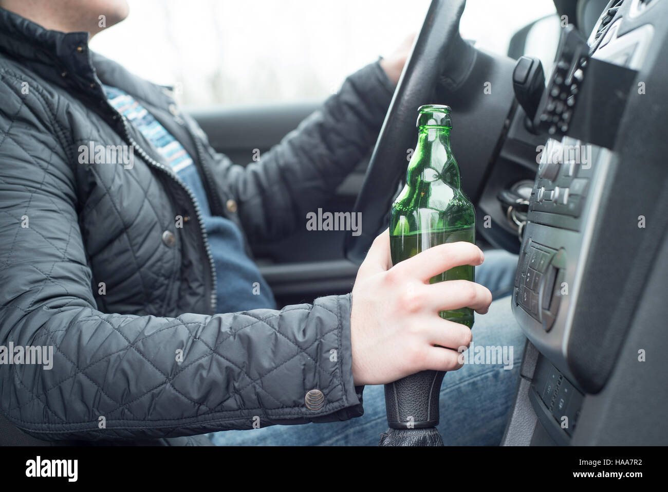 Jeune homme au volant de sa voiture alors que la consommation d'alcool Banque D'Images