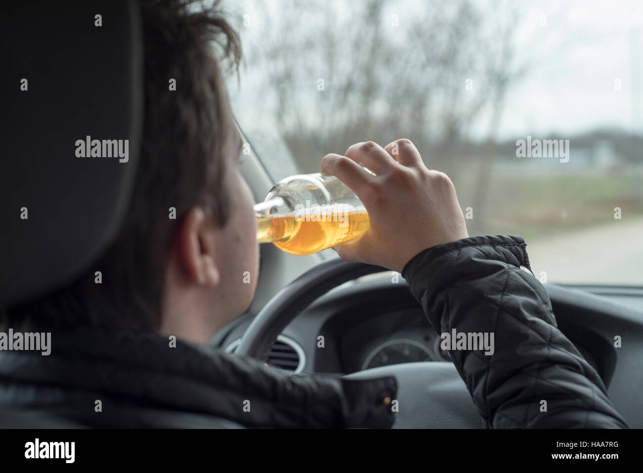 Jeune homme au volant de sa voiture alors que la consommation d'alcool Banque D'Images