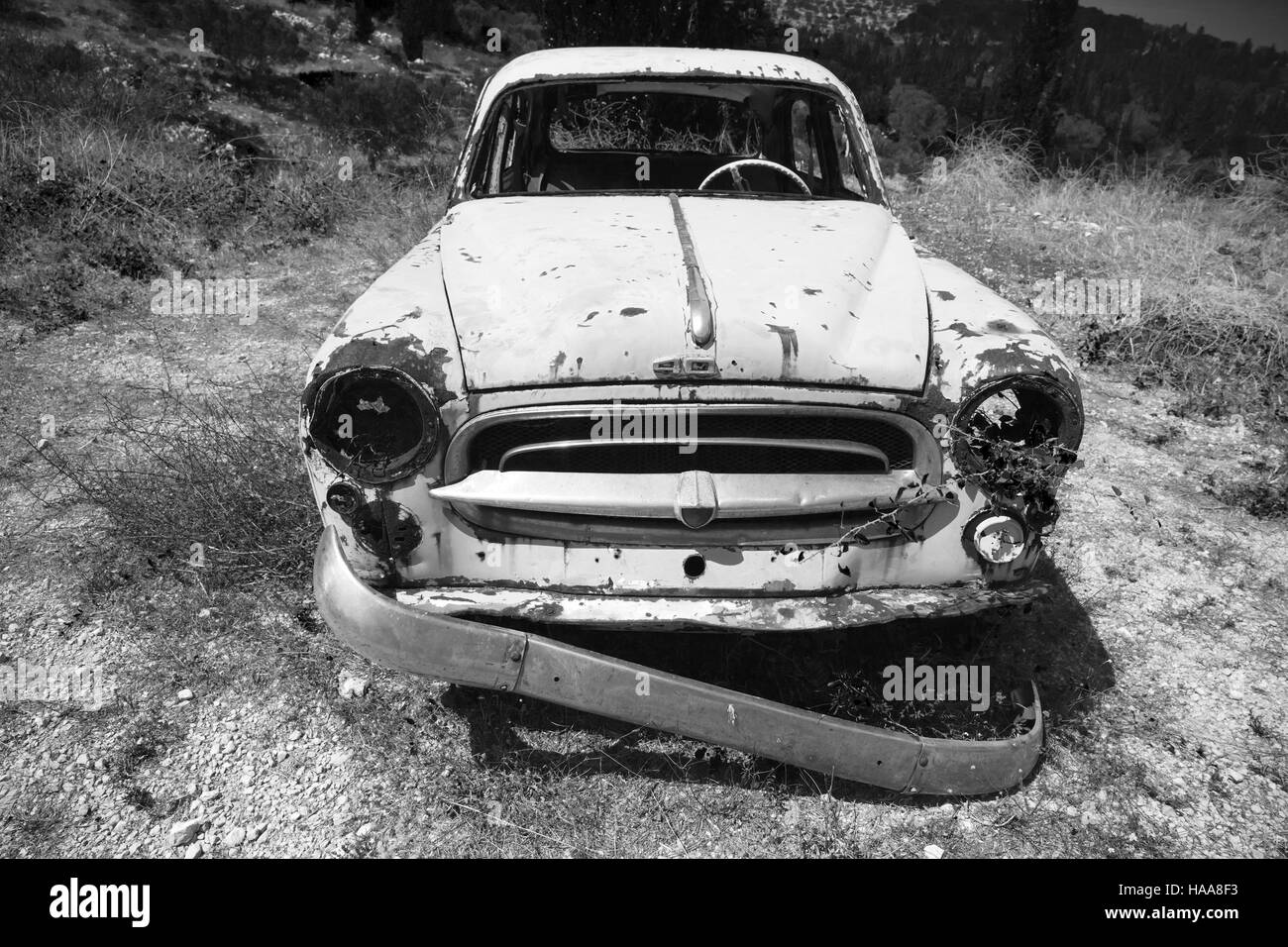 Zakynthos, Grèce - 20 août 2016 : Vieille voiture rouillée abandonnée se trouve dans un jardin d'été, vue de face, noir et blanc Banque D'Images