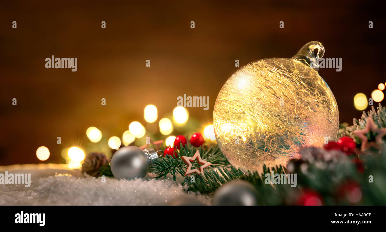 Libre d'une boule de noël transparente, branches de sapin et des ornements sur la neige, avec les feux de flou artistique et de l'espace de copie sur le bois à l'arrière-plan Banque D'Images