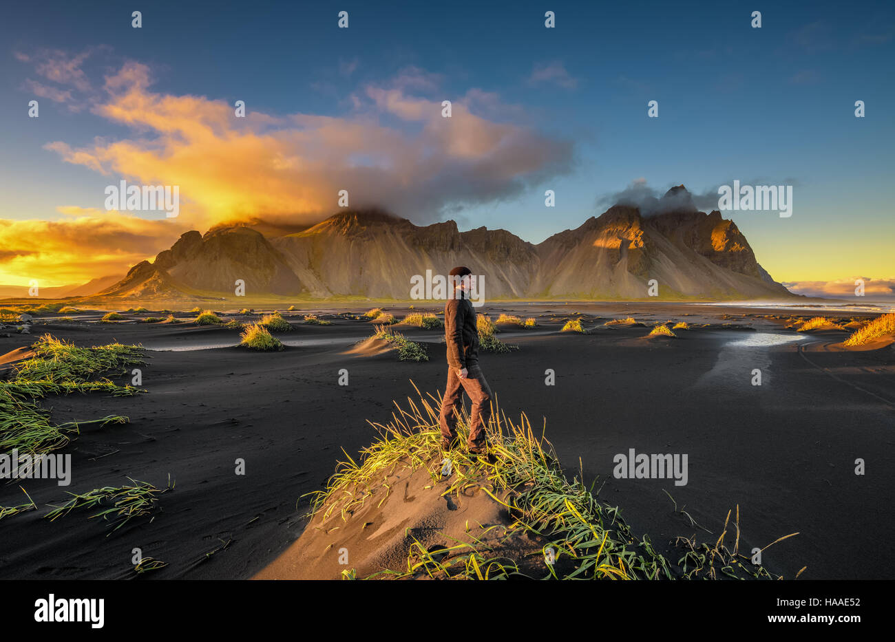 Coucher du soleil à Vestrahorn randonneur profitant de la montagne (Batman) et de sa plage de sable noir en Islande Banque D'Images
