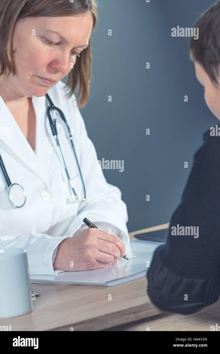 Docteur en médecine de prescription thérapie écriture female patient in hospital Office après examen médical Banque D'Images