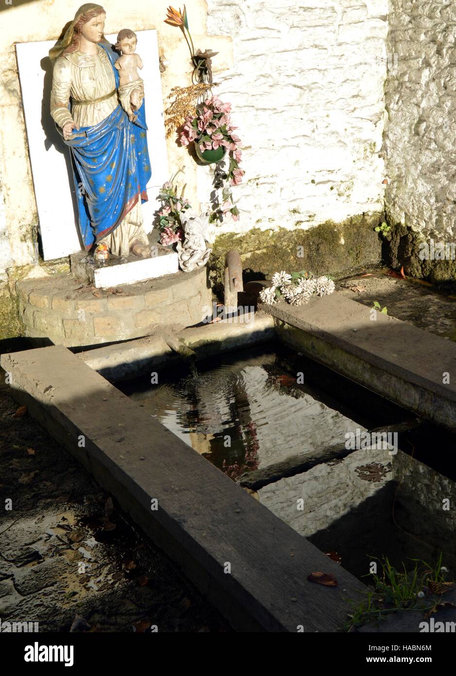 Vierge Marie et l'Enfant Jésus sur une ancienne fontaine à eau avec une cuve à lessive Banque D'Images