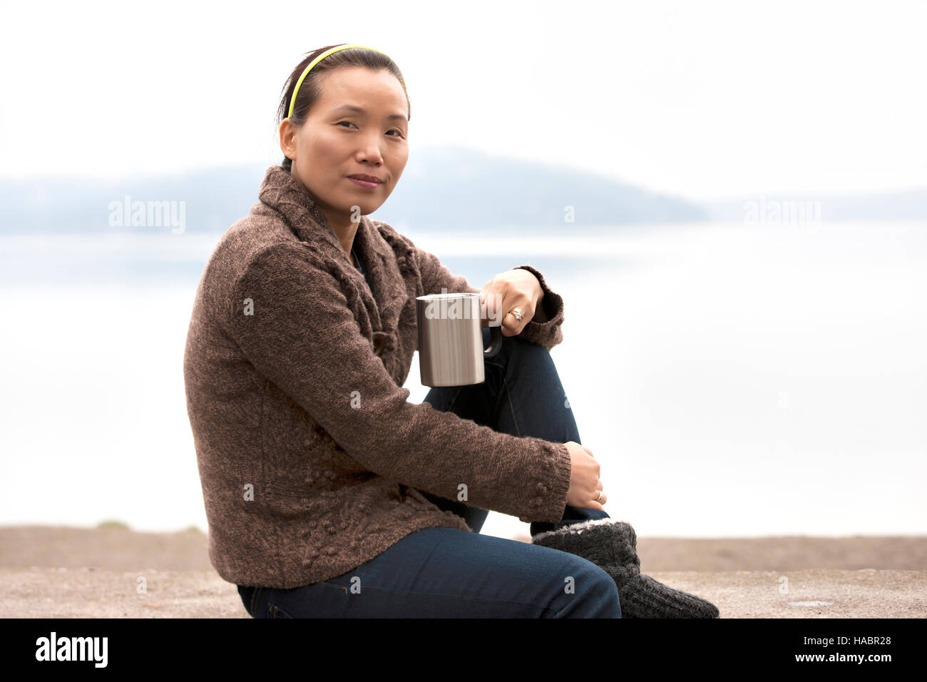 Femme Asiatique jouit de café par lac. Banque D'Images Femme Asiatique jouit de café par lac. Banque D'Images