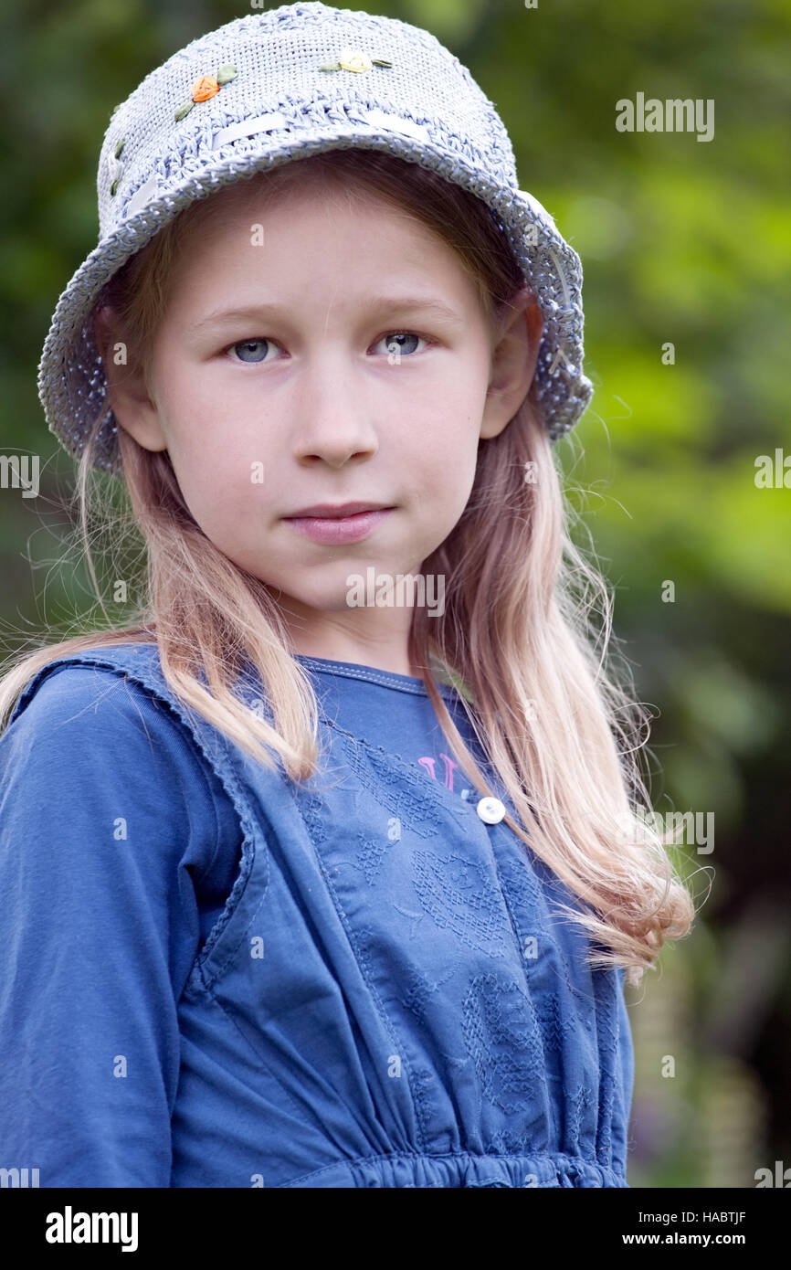 Petite fille en bleu hat portrait sur fond d'été vert Banque D'Images