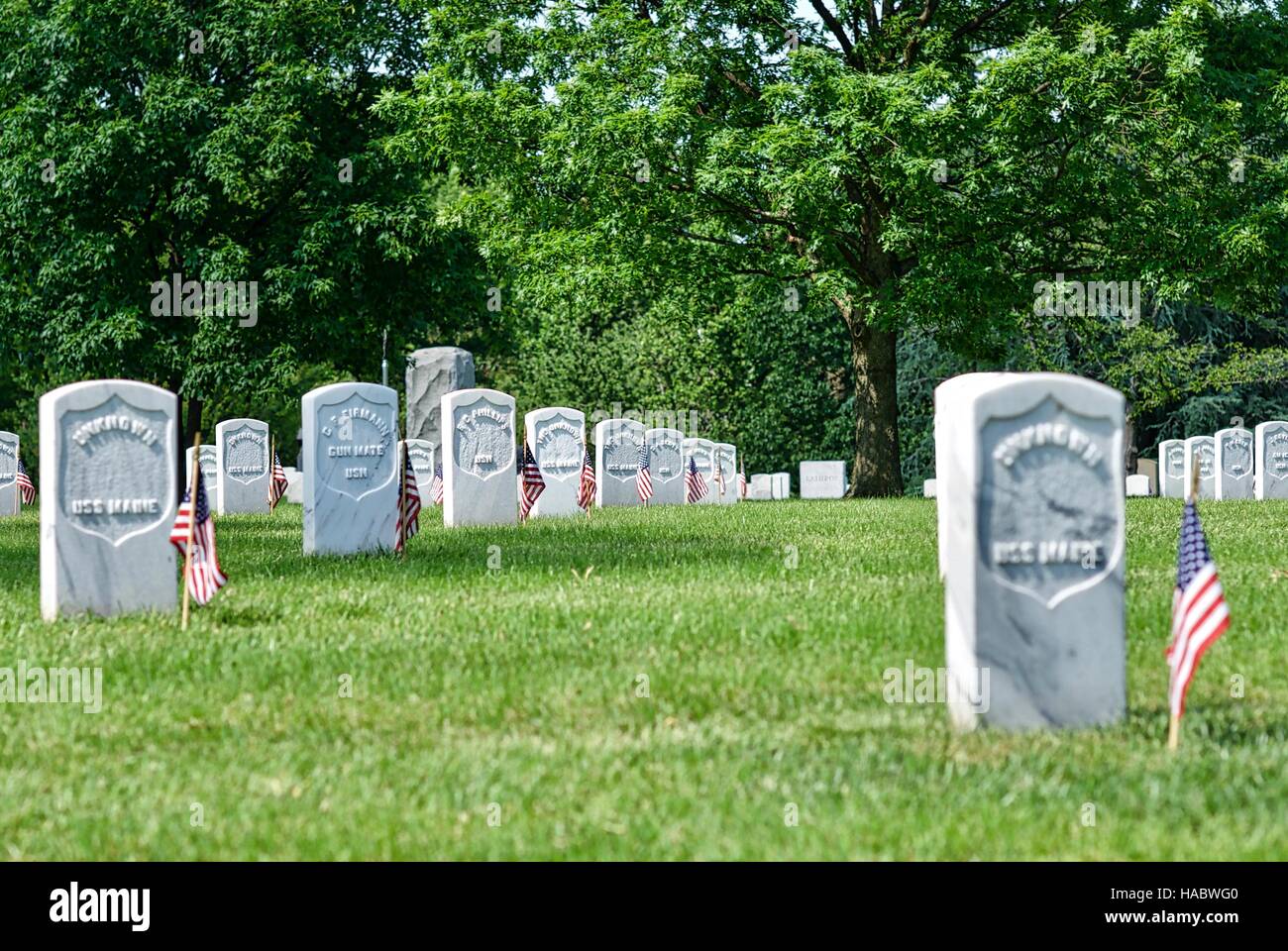 Les rangées de pierres tombales avec le drapeau américain au cimetière national d'Arlington, Arlington, Virginia, USA, le week-end du Memorial Day. Banque D'Images
