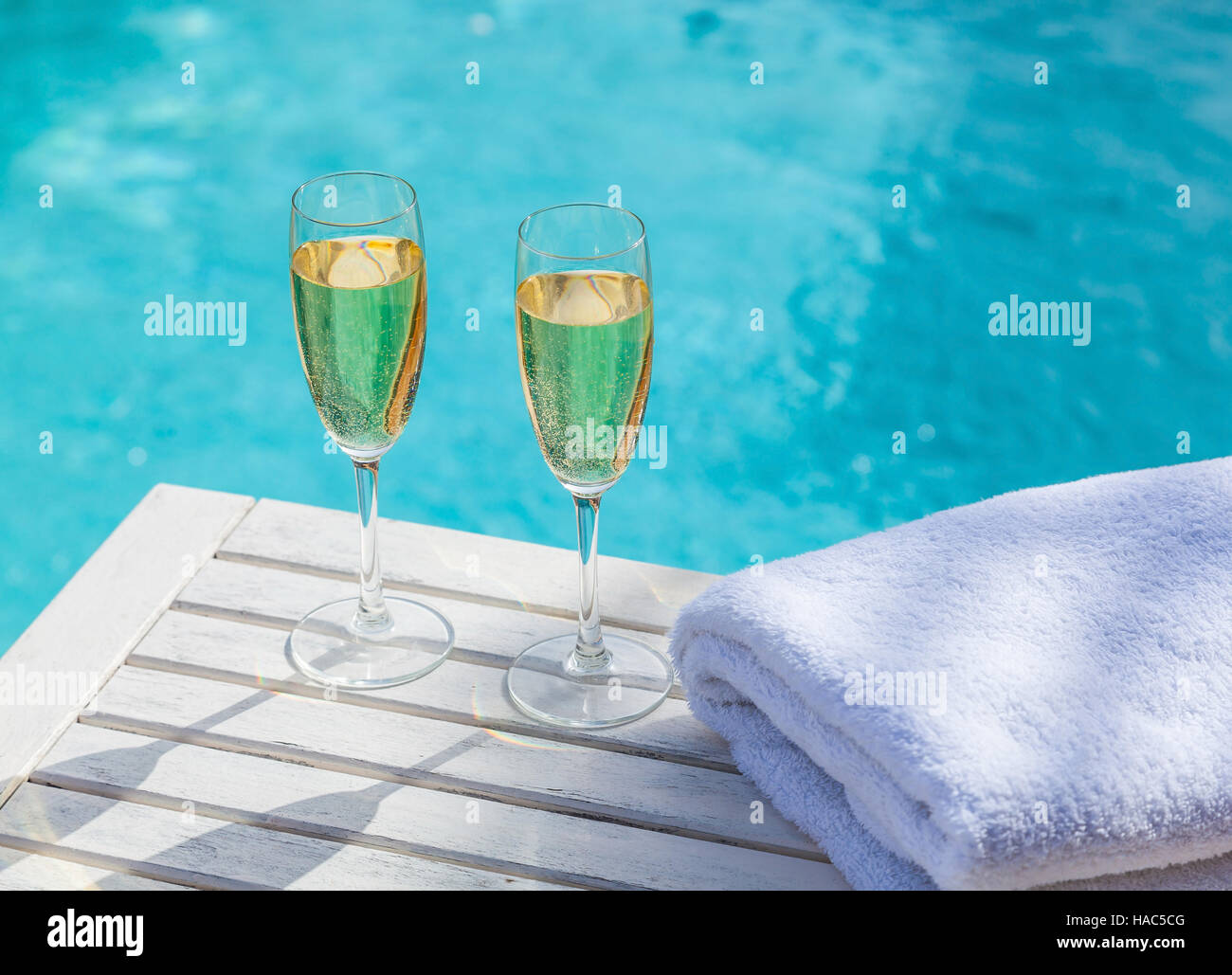 Deux verres de champagne sur une table en bois blanc, à côté de la piscine en été. Banque D'Images