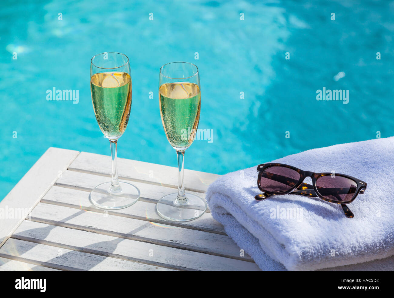 Deux verres de champagne sur une table en bois blanc, à côté de la piscine en été. Banque D'Images