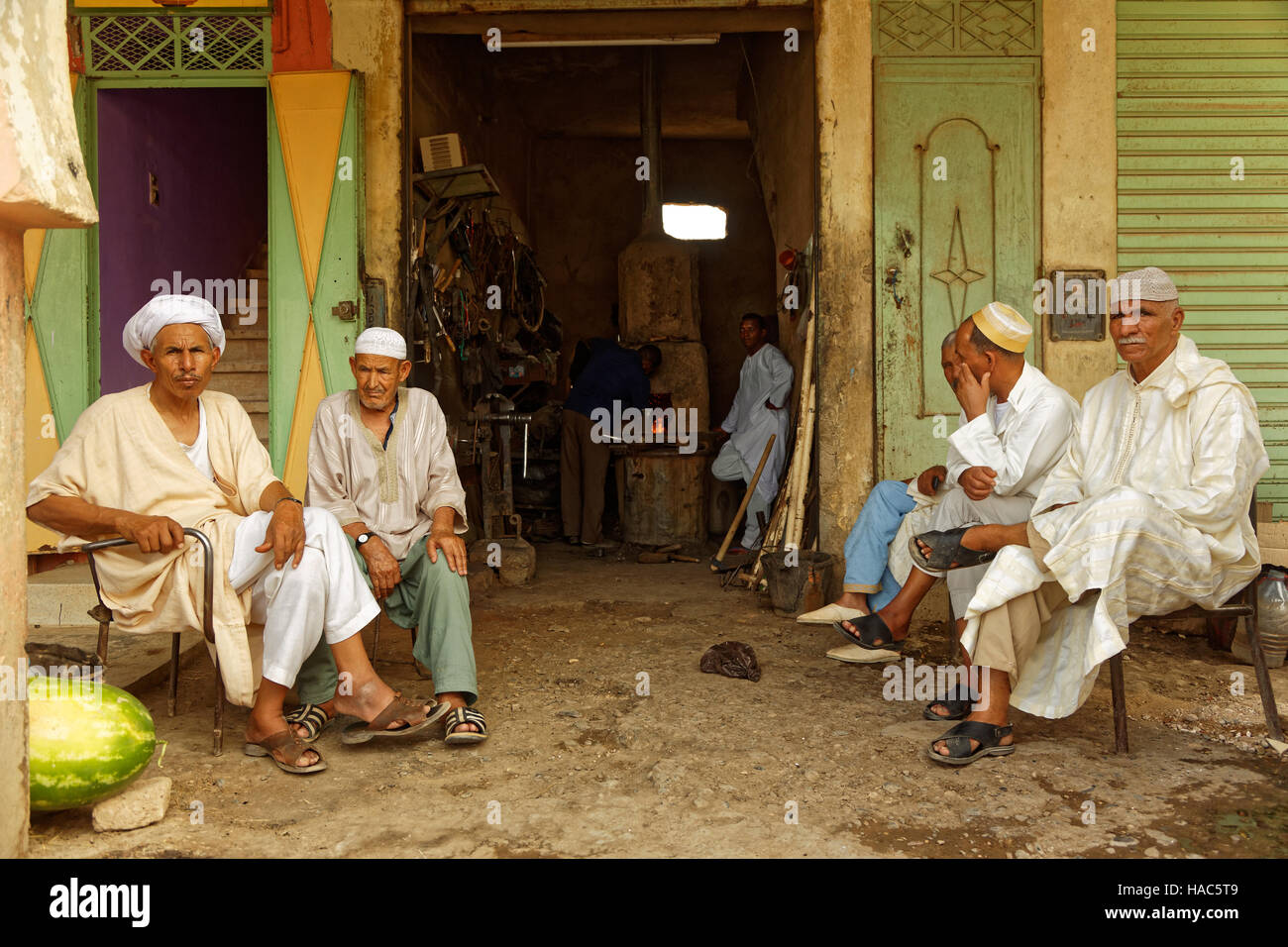 Vieux hommes marocains avec leurs vêtements traditionnels s'asseoir devant le forgeron et passer un peu de temps tout en discutant. Banque D'Images