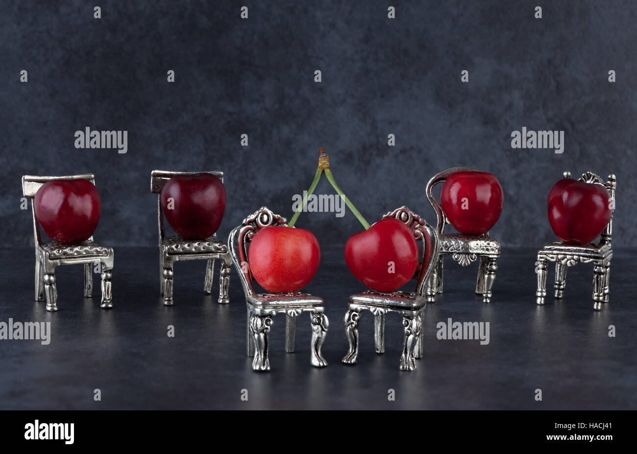 Délicieux rouge cerises mûres sur les petites chaises vintage argent et fond sombre Banque D'Images