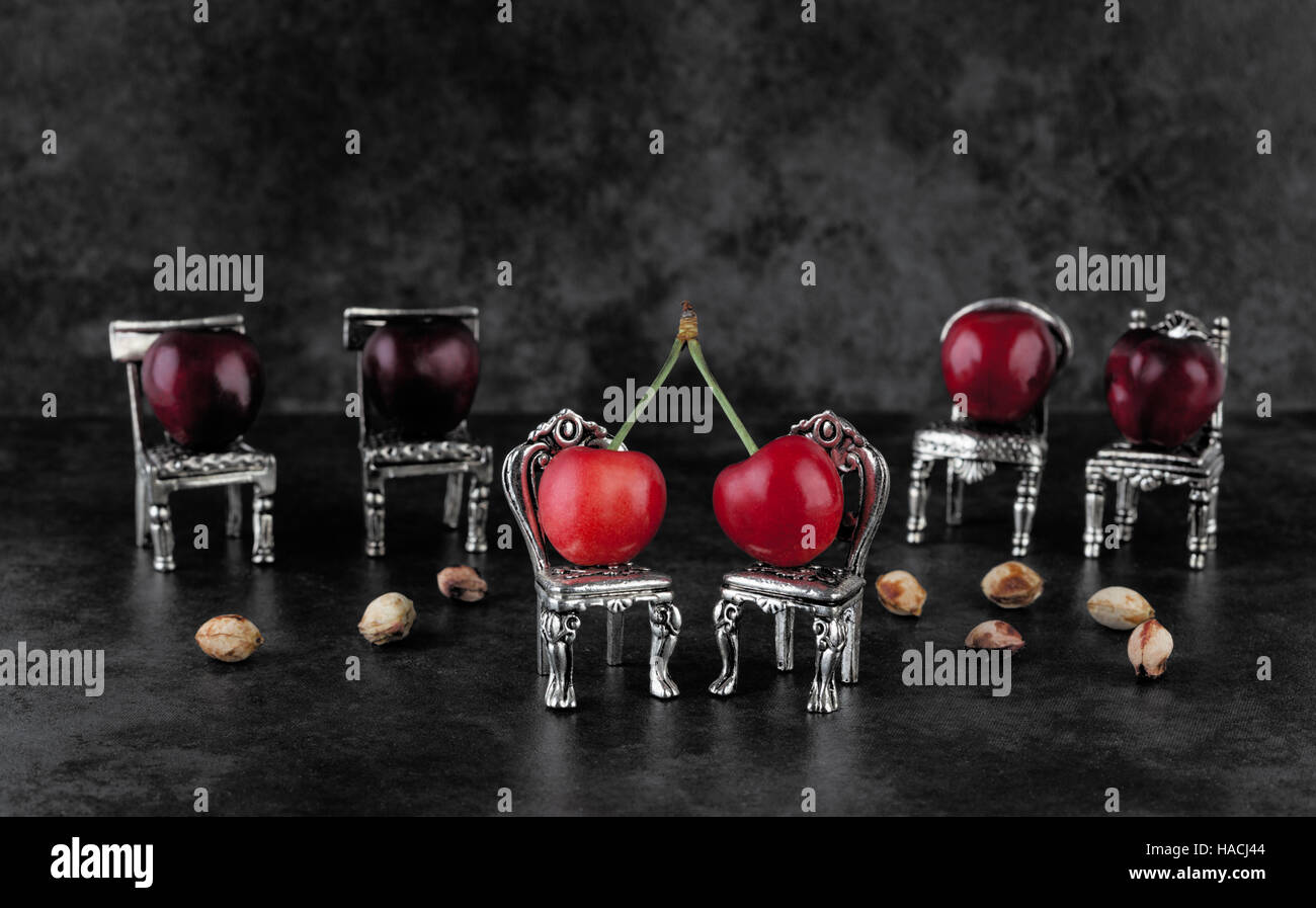 Délicieux rouge cerises mûres sur vintage argent petites chaises avec cherrystones sur fond sombre with copy space Banque D'Images