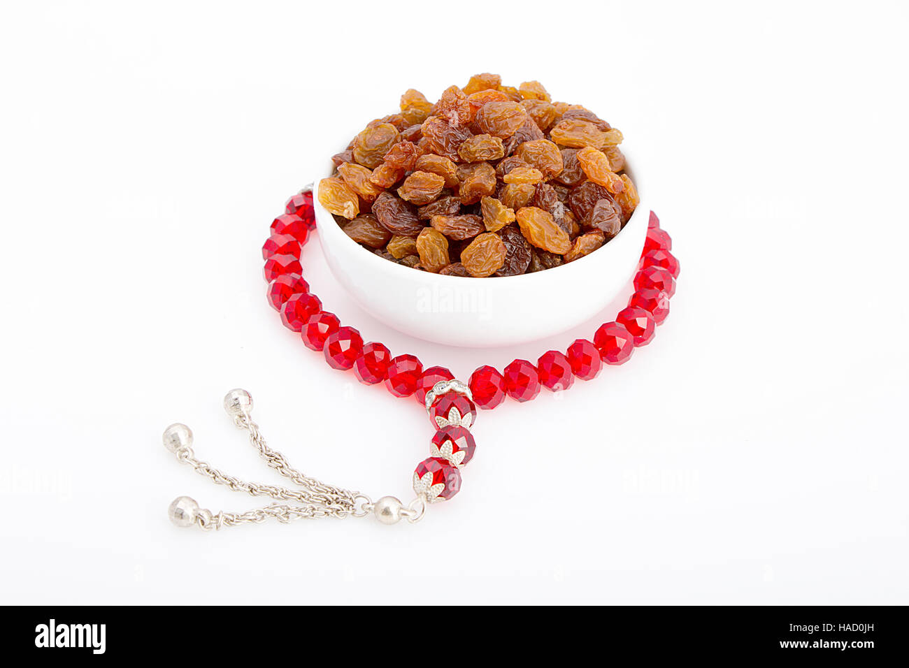 Raisins séchés dans une assiette blanche avec un chapelet rouge autour pour le petit-déjeuner dans le Ramadan Banque D'Images